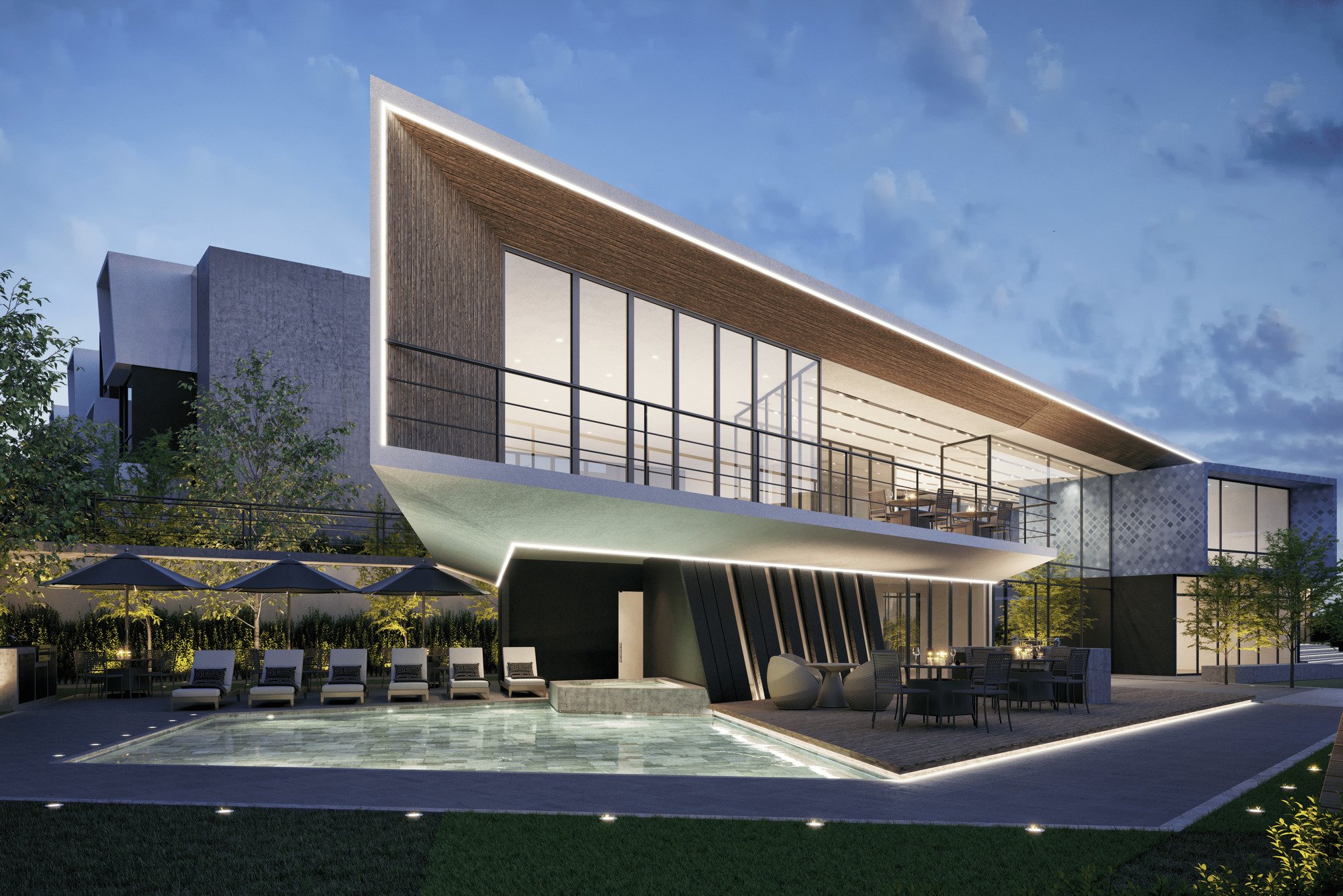 Edificio moderno de varias plantas, con fachada de cristal y detalles de madera, iluminado en la noche, con área de piscina y mobiliario exterior, rodeado de árboles y vegetación.