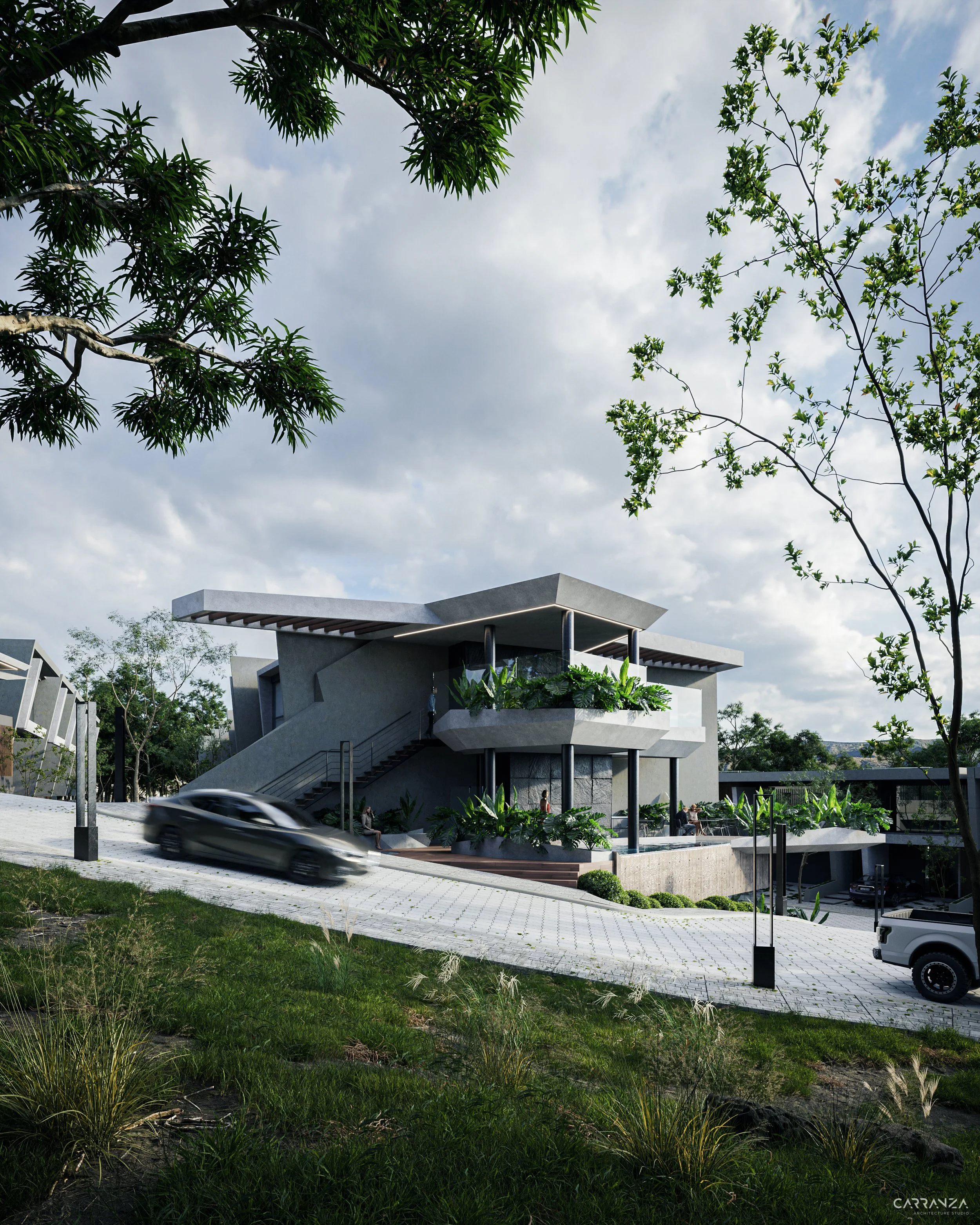 Edificio moderno de dos pisos con amplios balcones, rodeado de vegetación y árboles, con un camino de piedra en pendiente y autos estacionados.