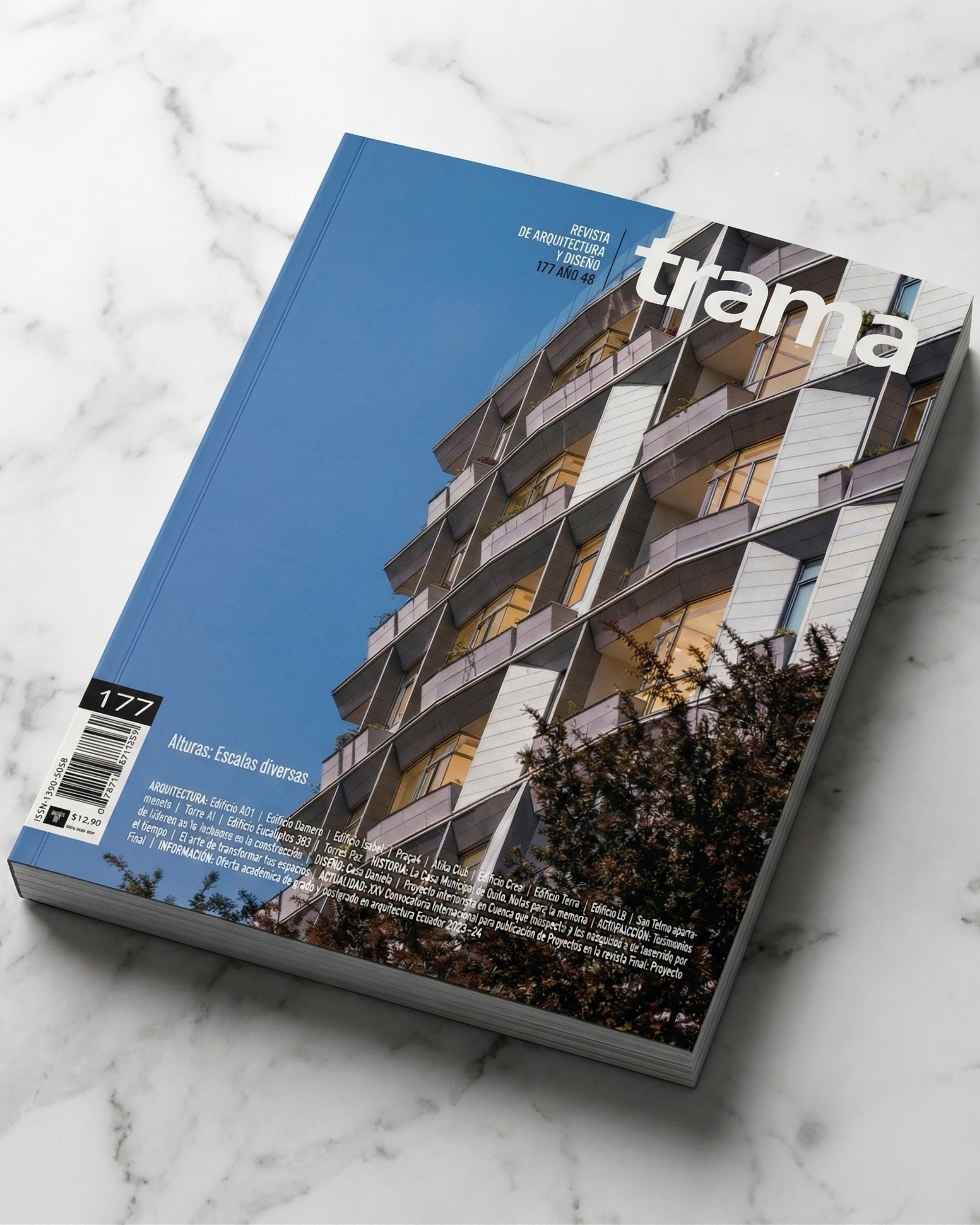 Revista Trama, sobre arquitectura, con imagen de edificio moderno con balcones en la portada, en una superficie de mármol blanco.