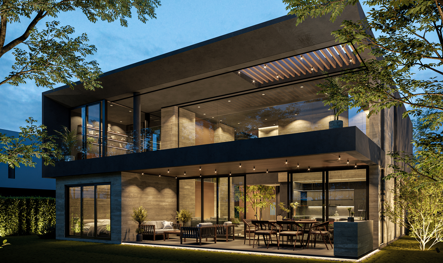 Casa moderna de dos pisos en la noche, con iluminación exterior, ventanales grandes, áreas de descanso en el patio con sillas y mesas, rodeada de árboles y césped.