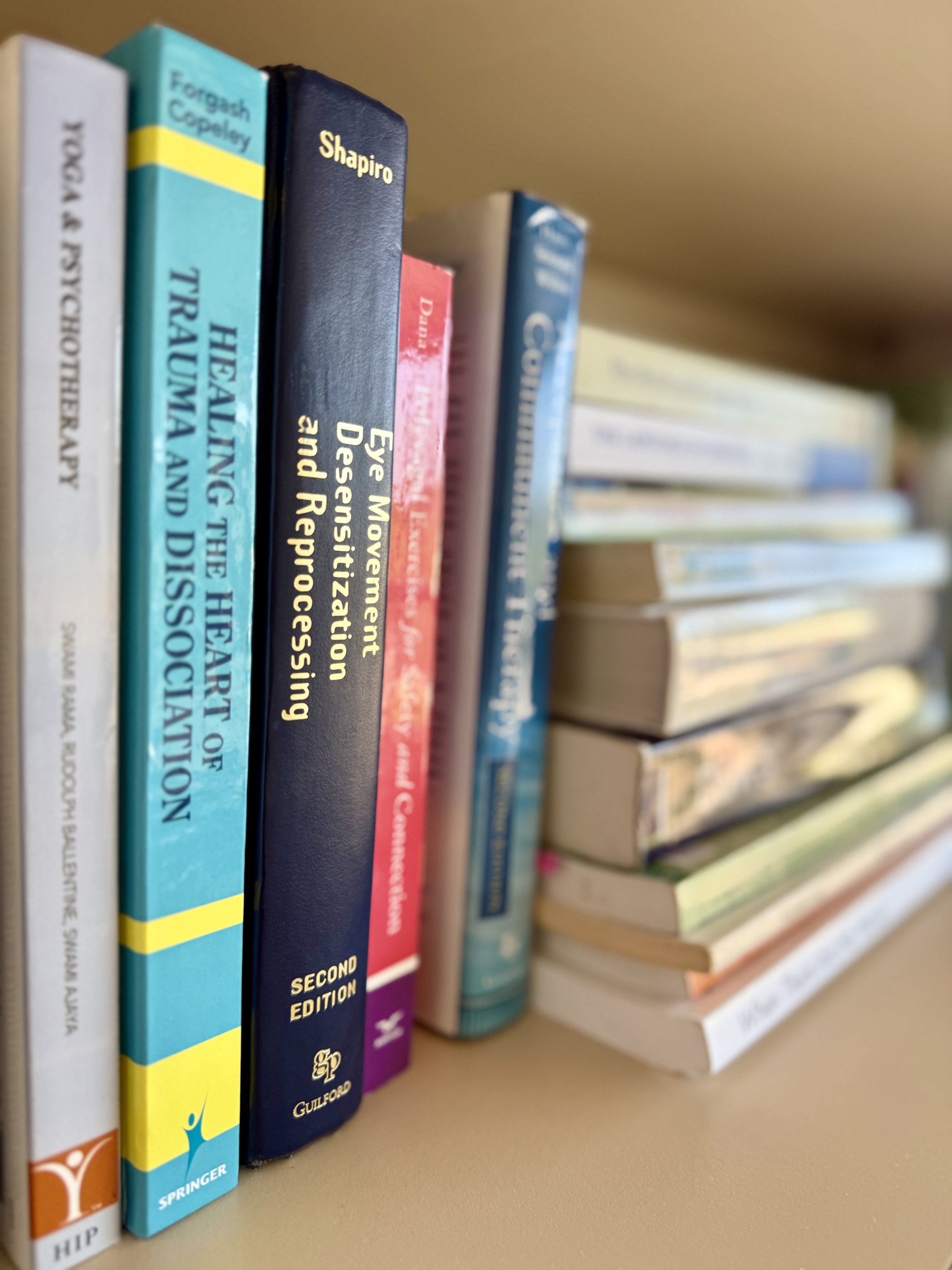 A shelf of books with various titles and colors, including one titled 'Eye Movement Desensitization and Reprocessing' and others related to psychology and therapy.