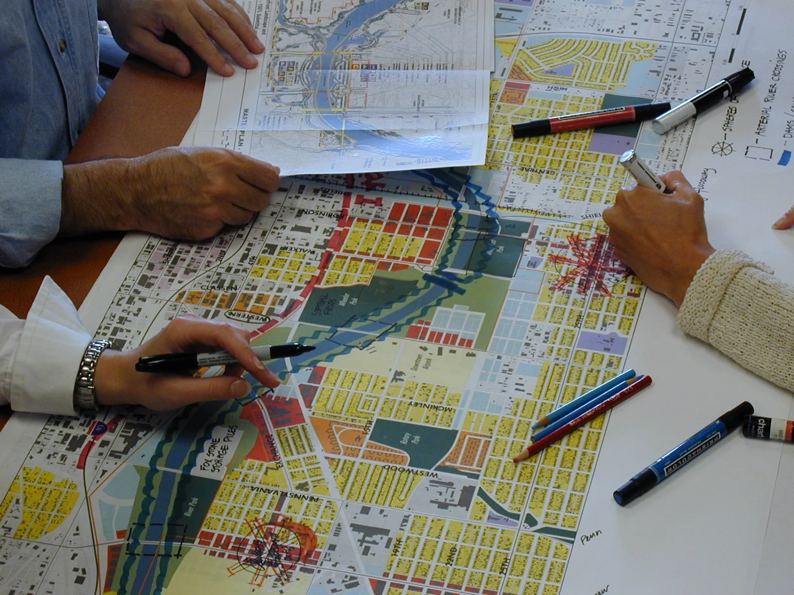 People analyzing city maps and planning using pens and markers.