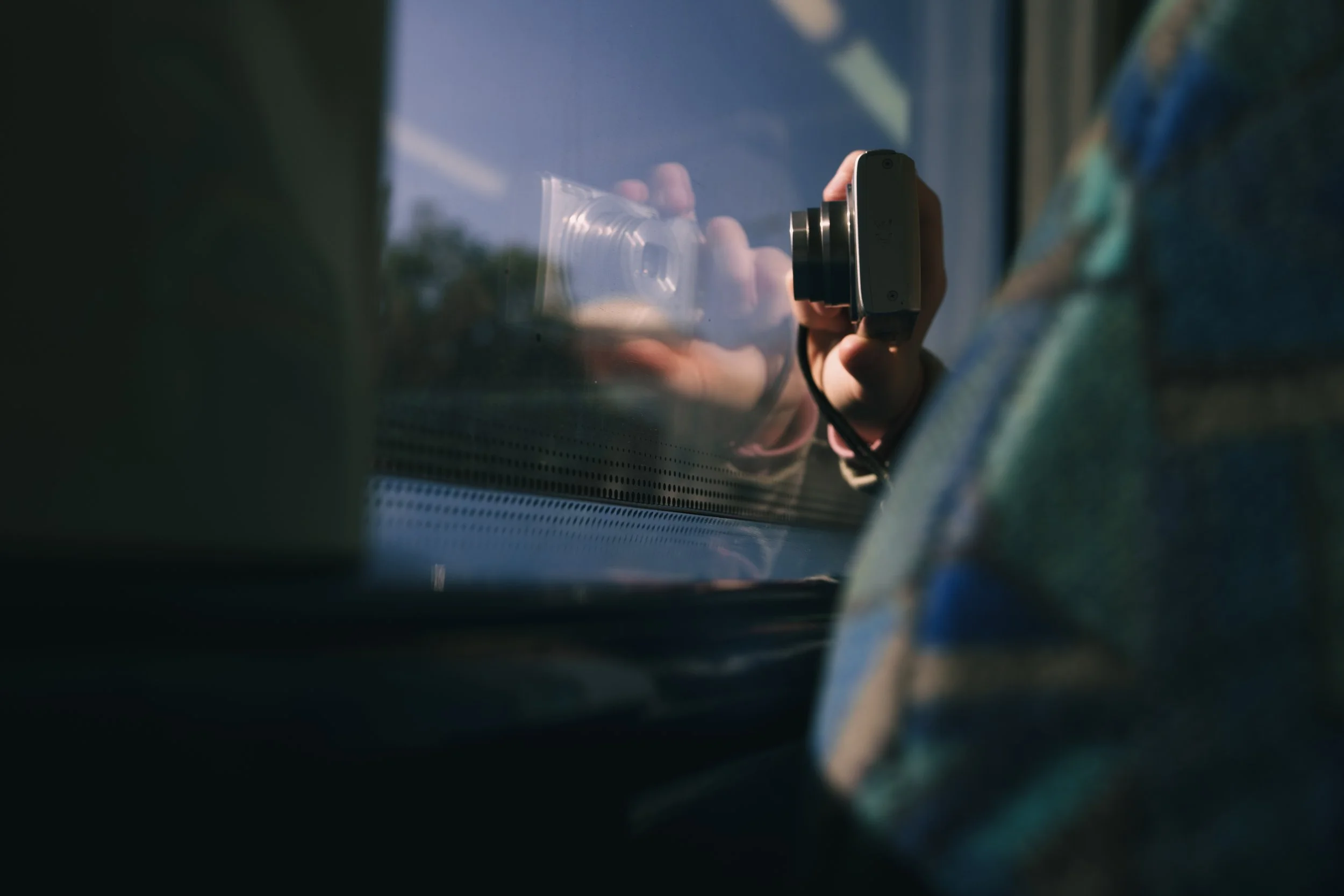 Person taking a photo through a train window with a camera