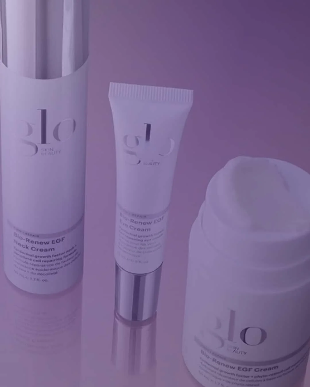Three skincare products from the brand glo, including a large cylindrical bottle, a tube, and a jar, placed against a purple background.