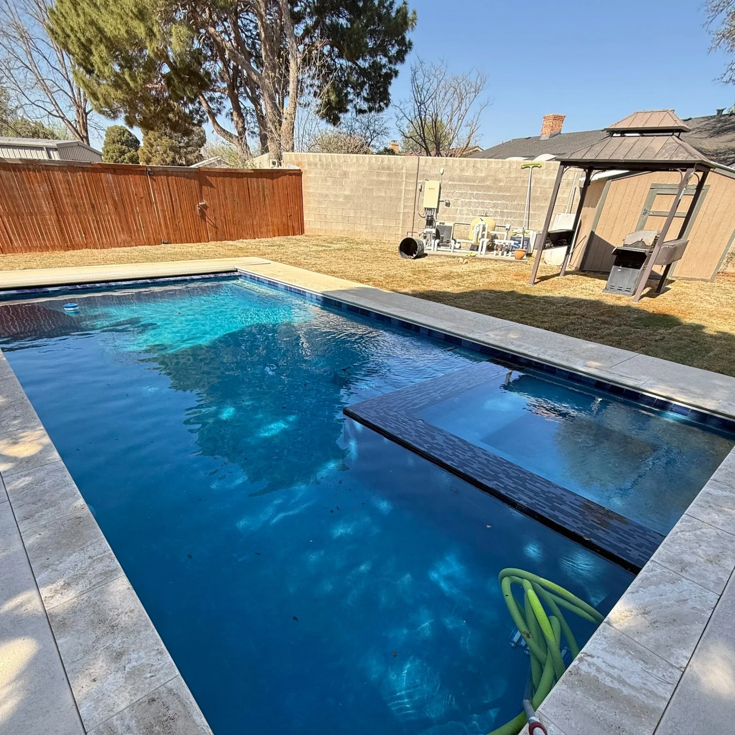 Backyard pool with visible equipment and spa system, highlighting professional pool equipment diagnostics and tech services in Midland, Texas.