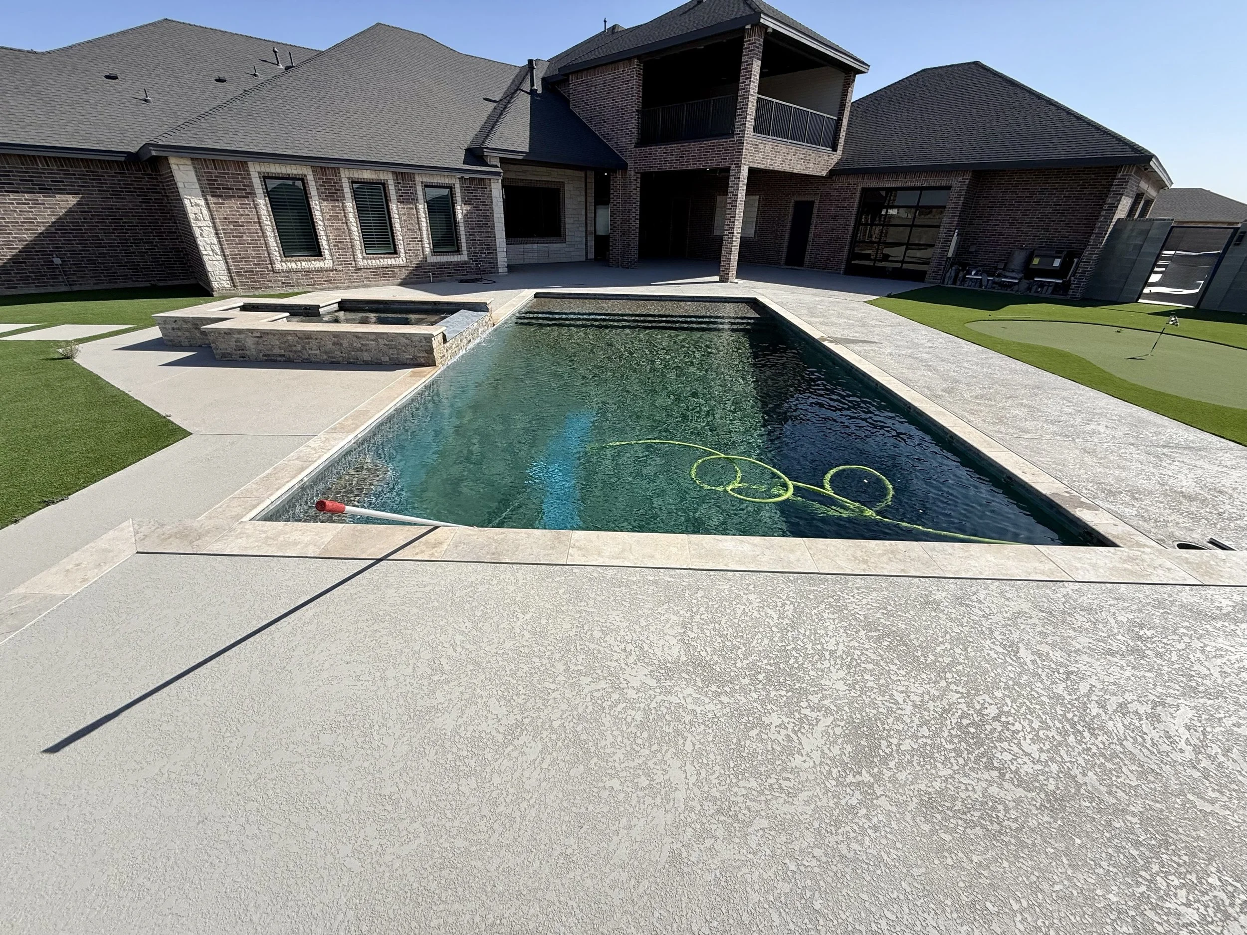 Backyard pool with cloudy water and cleaning tools before treatment in Midland, Texas.