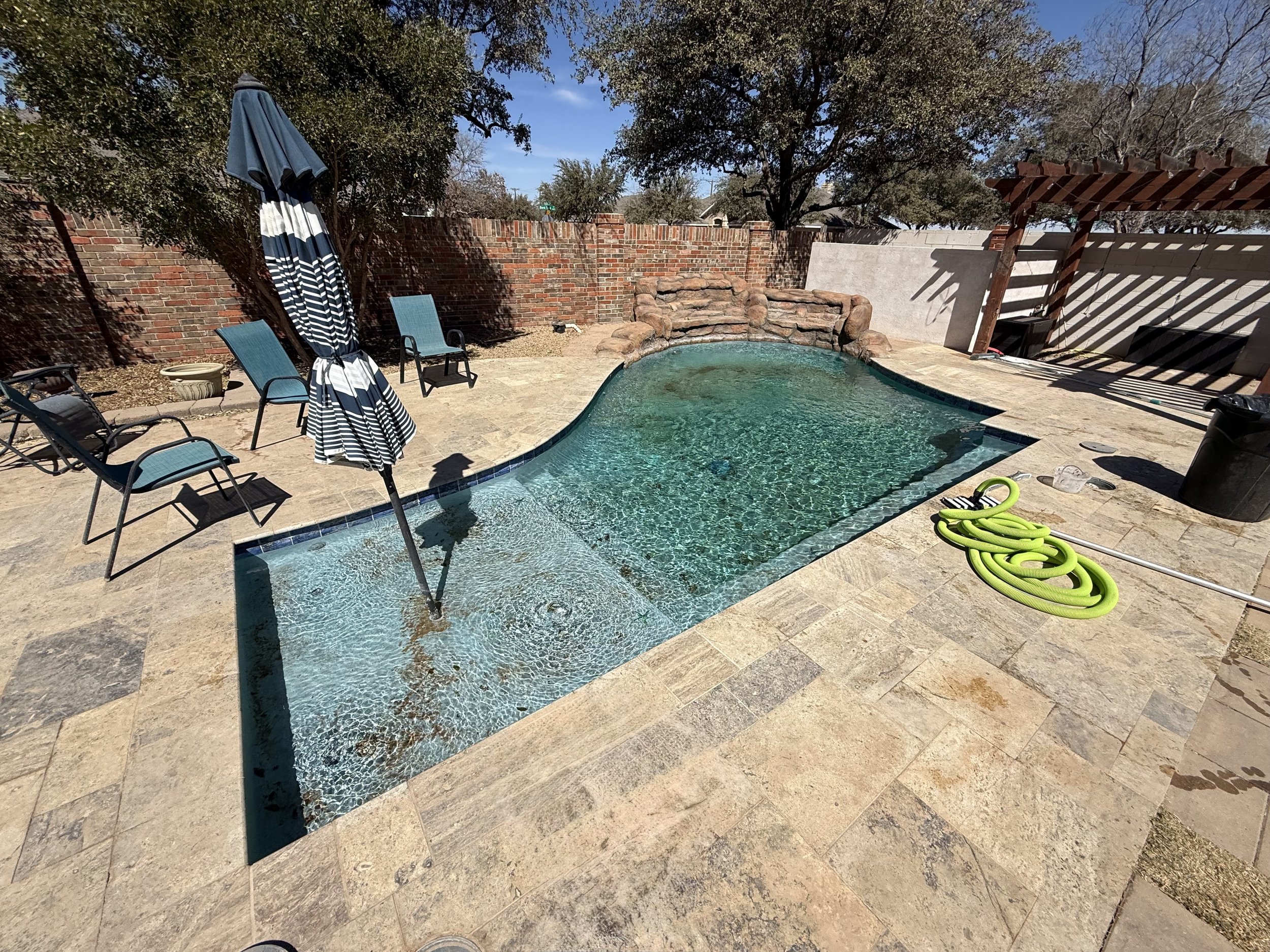 Residential pool in Midland, TX before cleaning service with debris and hose visible.