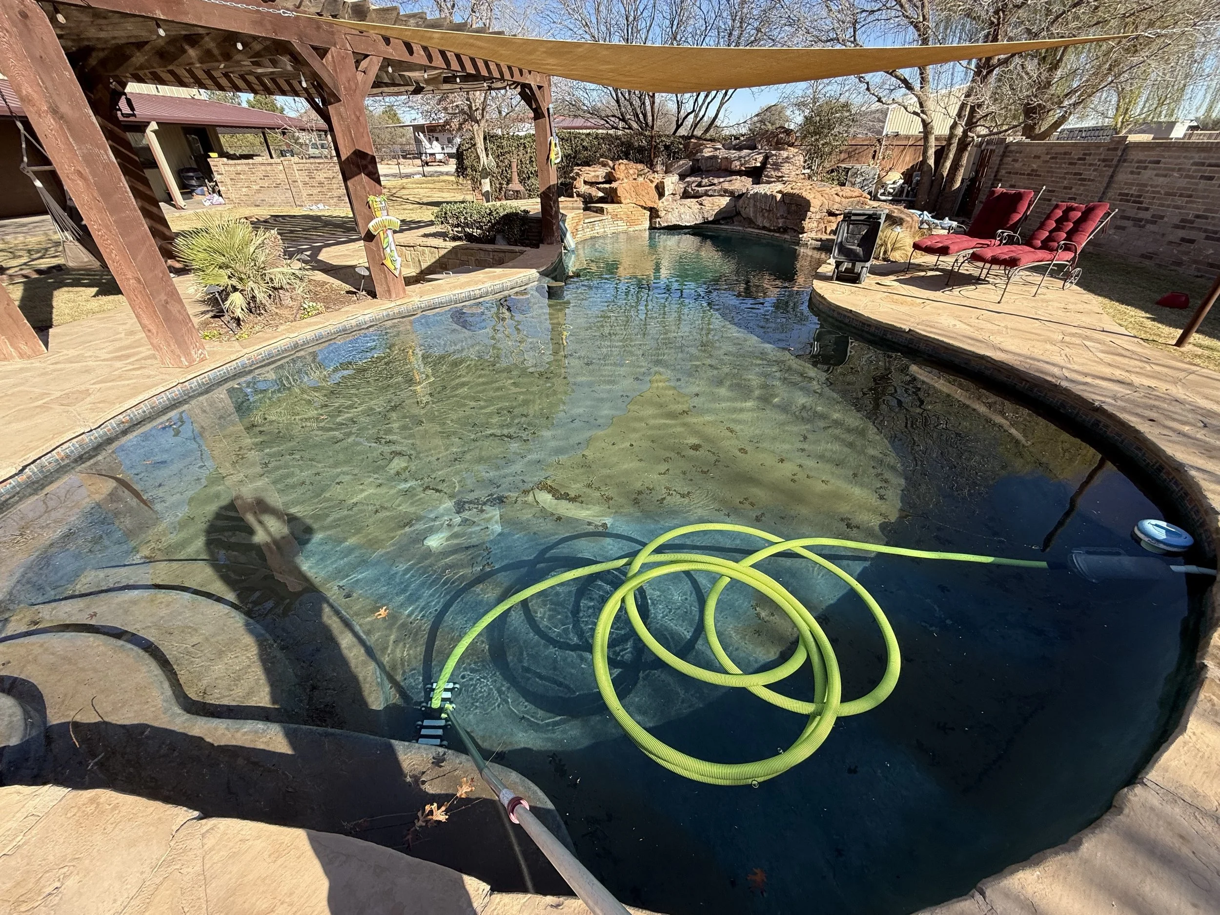 Pool with hose and debris visible before recovery cleaning in Midland, TX.