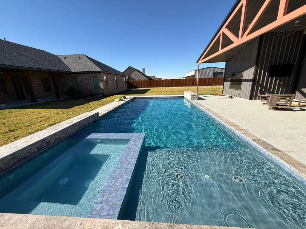 Long modern swimming pool with fully tiled spa and stone coping at a Midland home.