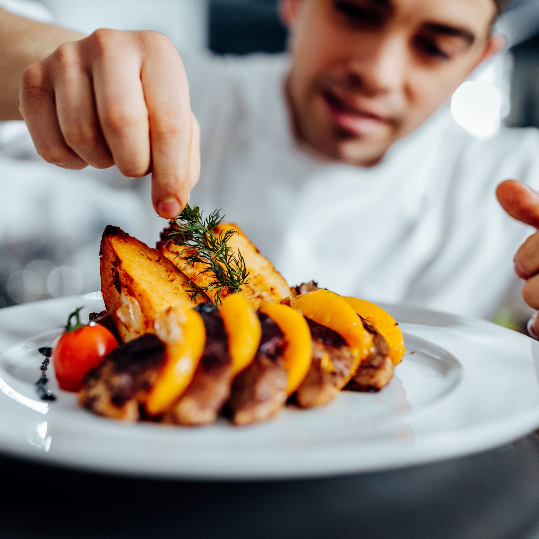 a chef adding garnish to a plate of beautifully crafted yellow squash