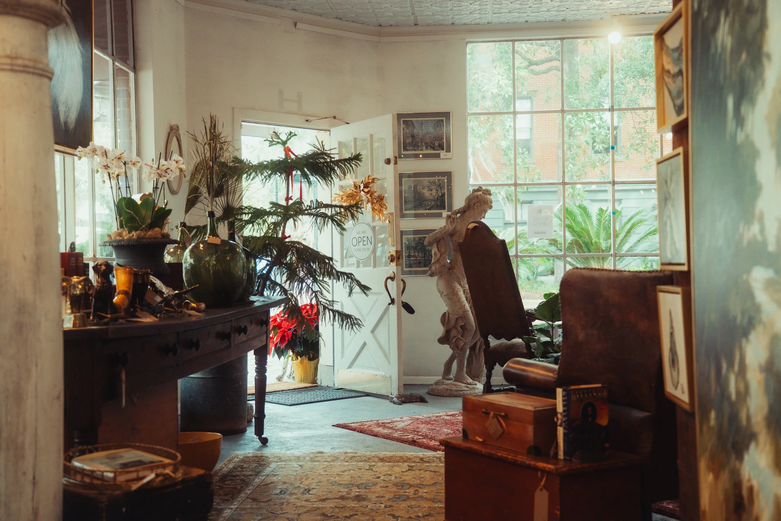 An elegant living room with a white marble fireplace, built-in bookcases, a blue velvet sofa, a yellow chair, a white armchair, and various decorative items including plants, gold accents, and artwork.