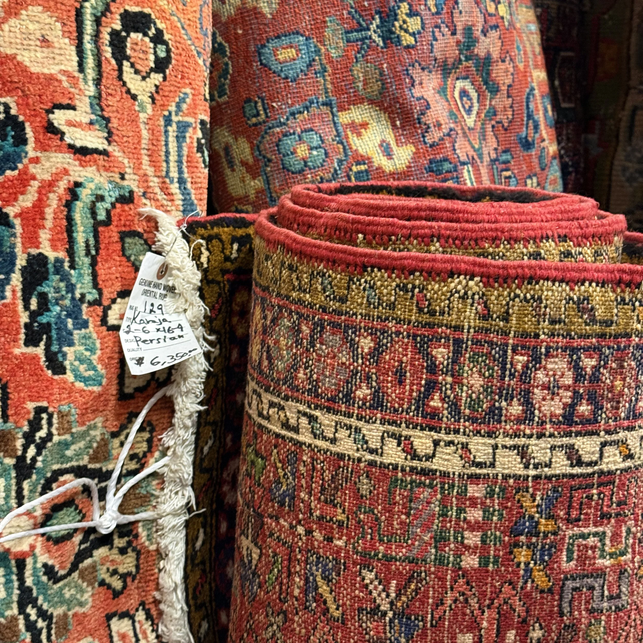 Rolled up Persian rugs with intricate patterns and vibrant colors, displayed in a store.