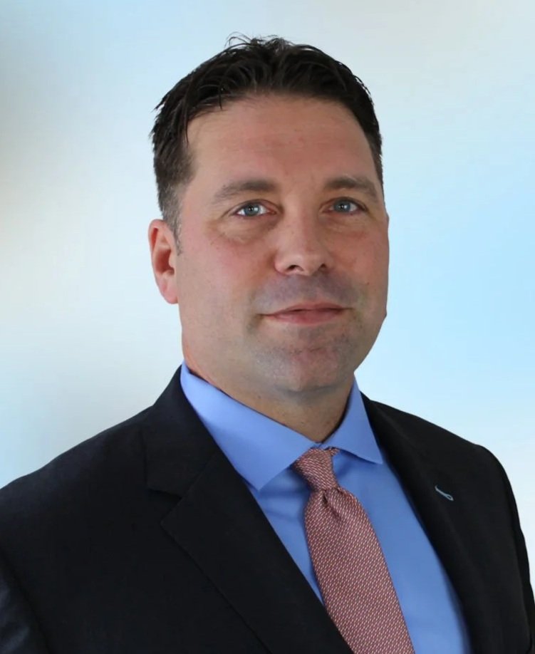 Portrait of a man in a suit and tie against a plain background.