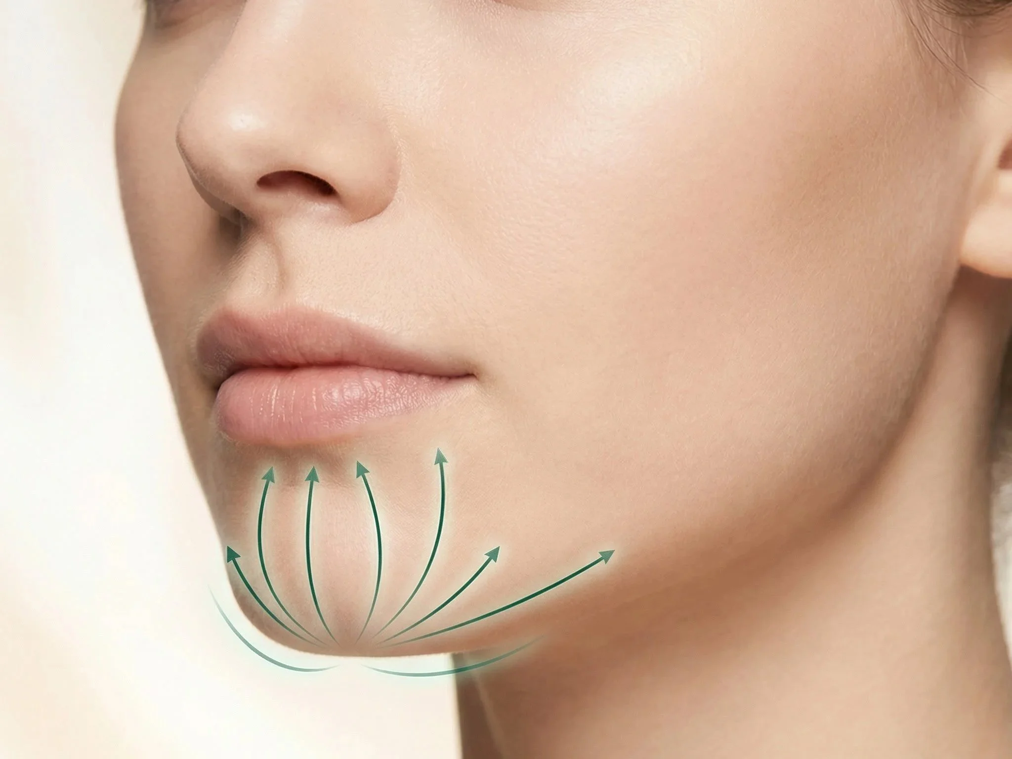 Close-up of a woman's face showing the chin and lower cheek area with directional arrows indicating facial massage or lifting upward.