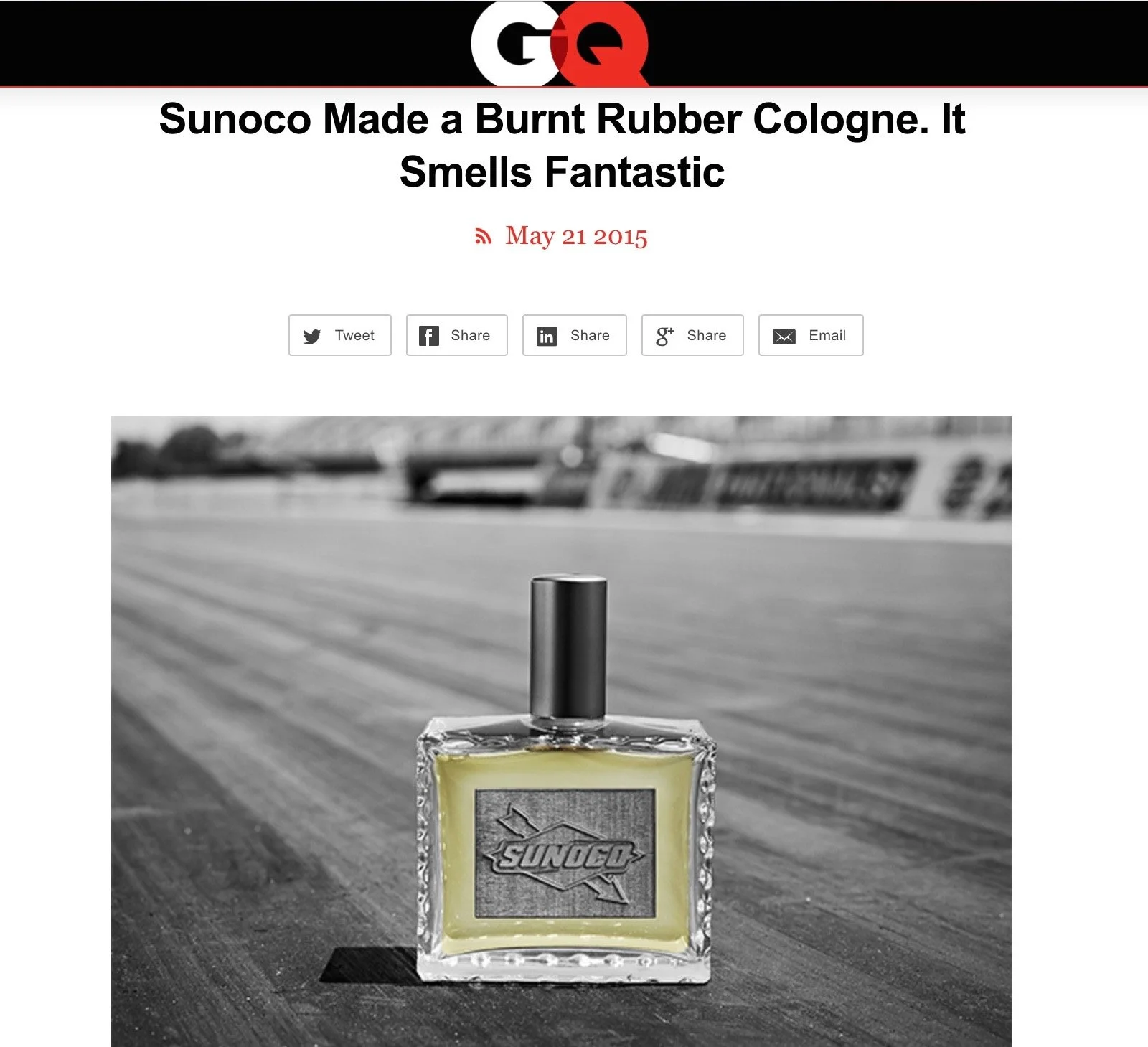 A picture of a GQ article highlighting the new Sunoco  burnt rubber cologne, placed on a motorsport track surface, with a blurred racetrack in the background.