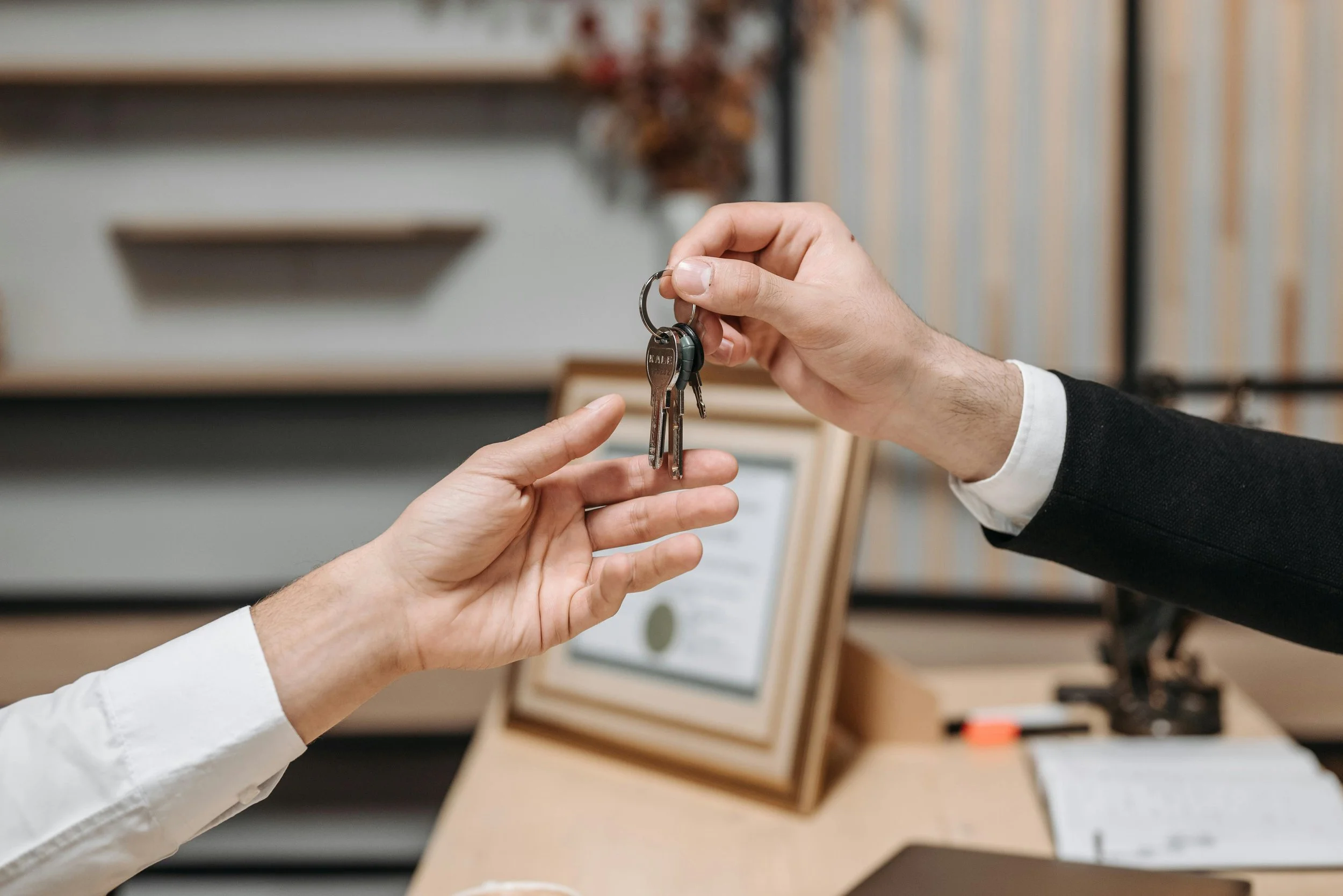 Person handing over a set of keys to another person in an office setting.