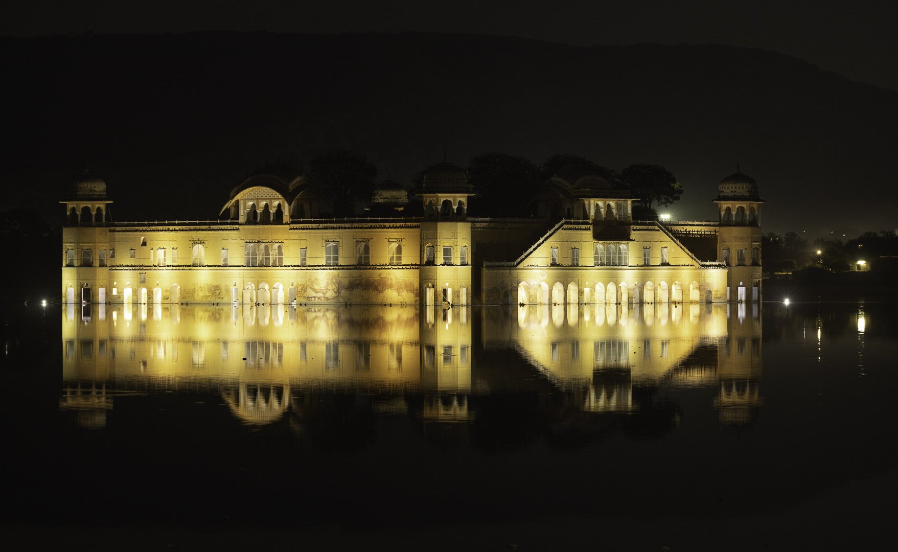 al Mahal illuminated at night, golden reflections on still water