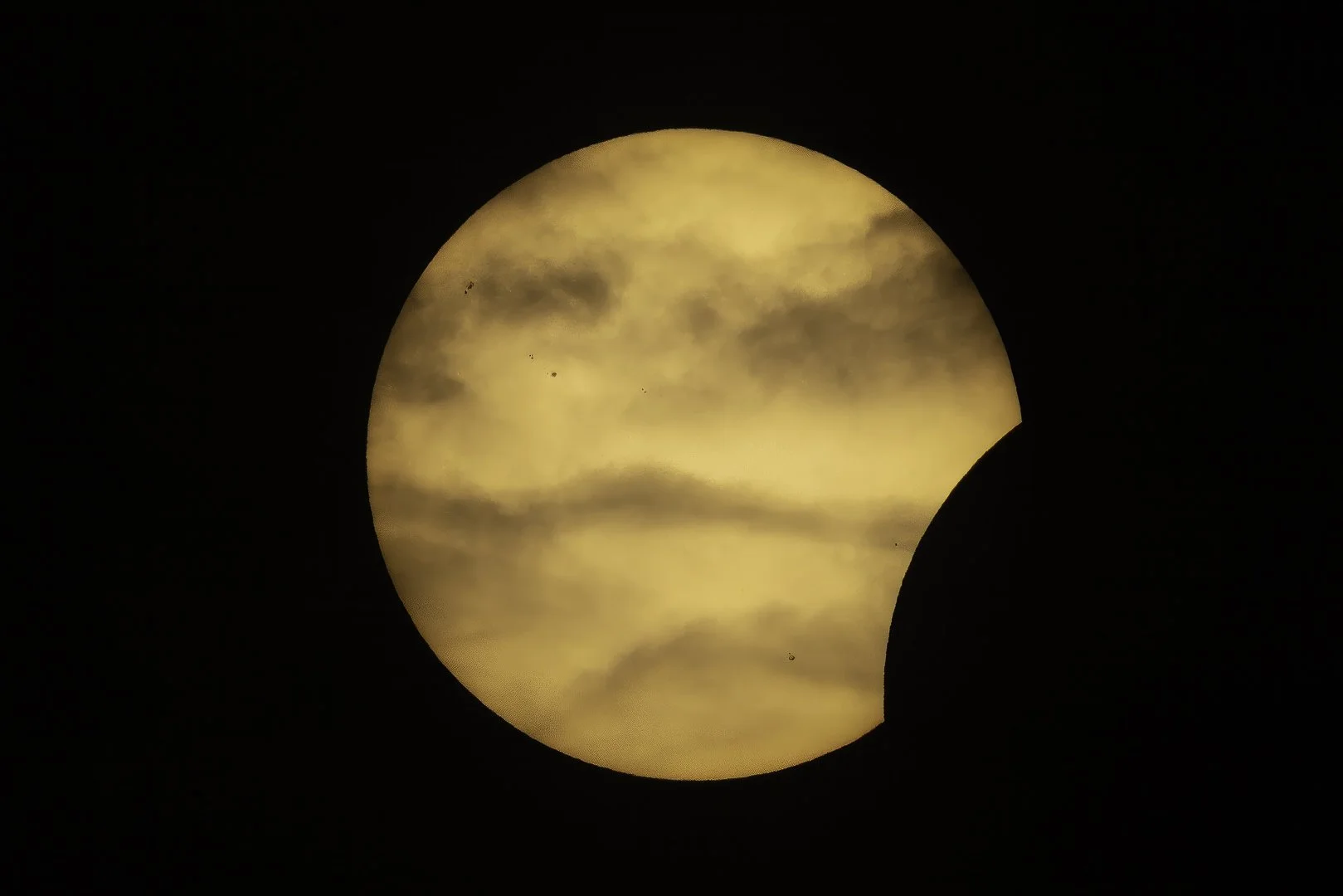 Partial solar eclipse on August 12th 2026 seen through thin clouds as the Moon crosses the Sun.