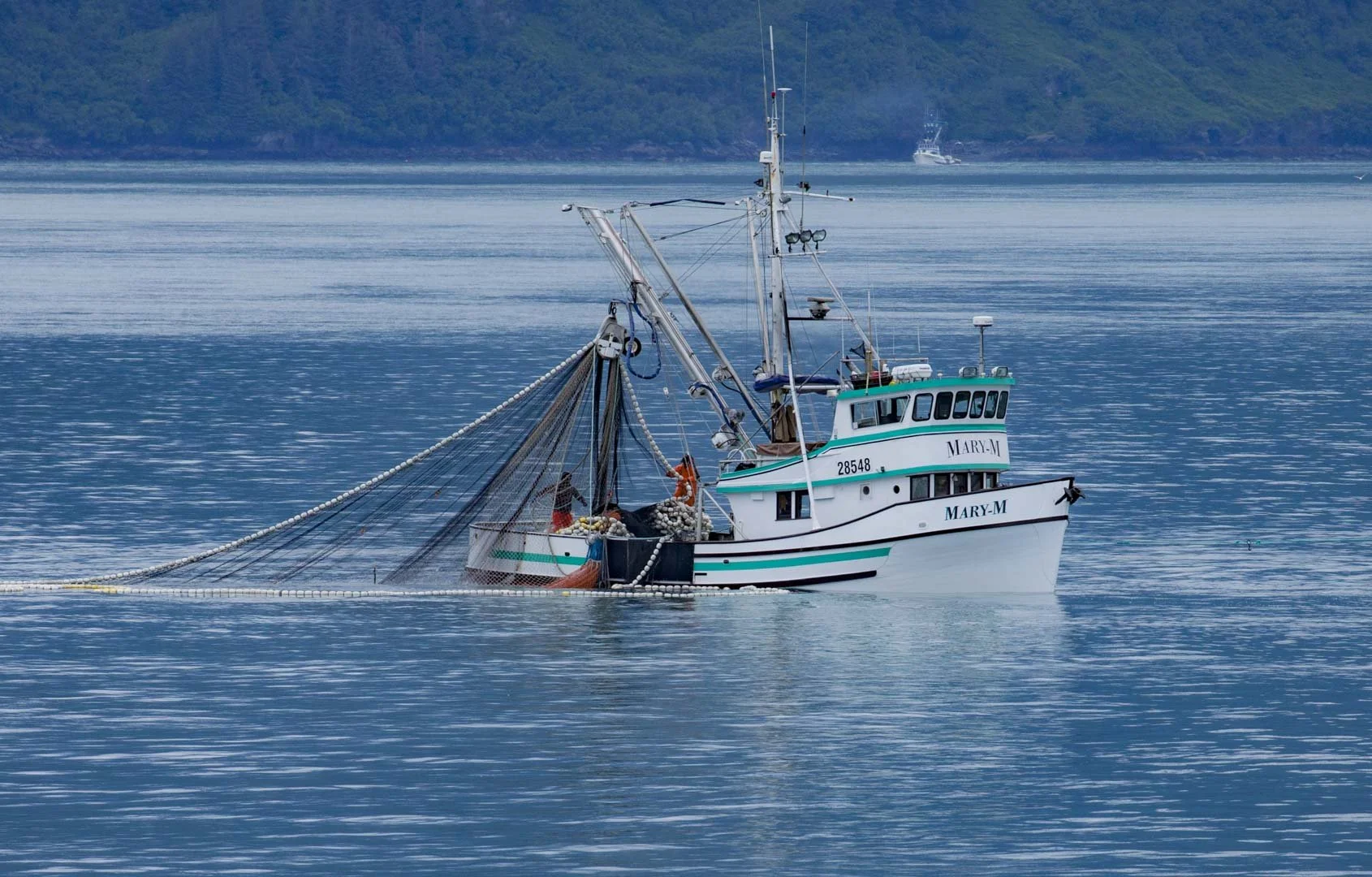 Fishing boat in the harbour of Valdez, Alaska, surrounded by the mountainous coastal landscape.