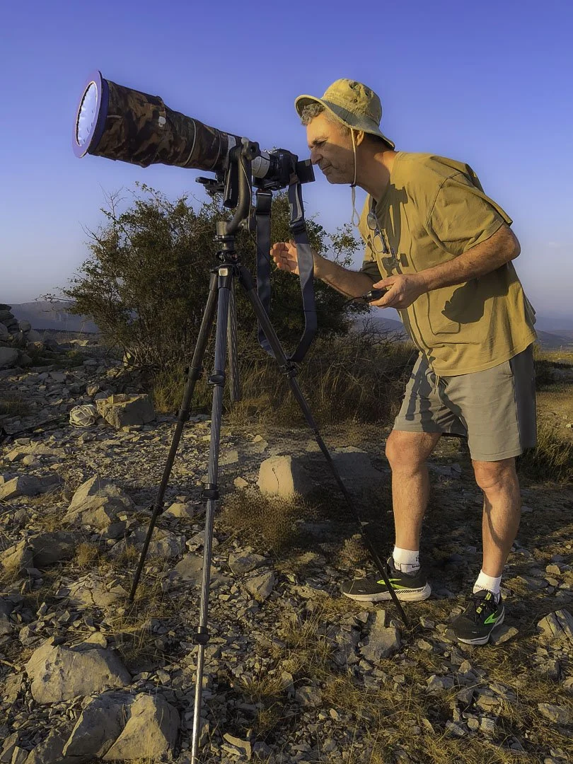 Joseph B photographing the solar eclipse on August 12th 2026, outdoors with a telephoto lens mounted on a tripod.