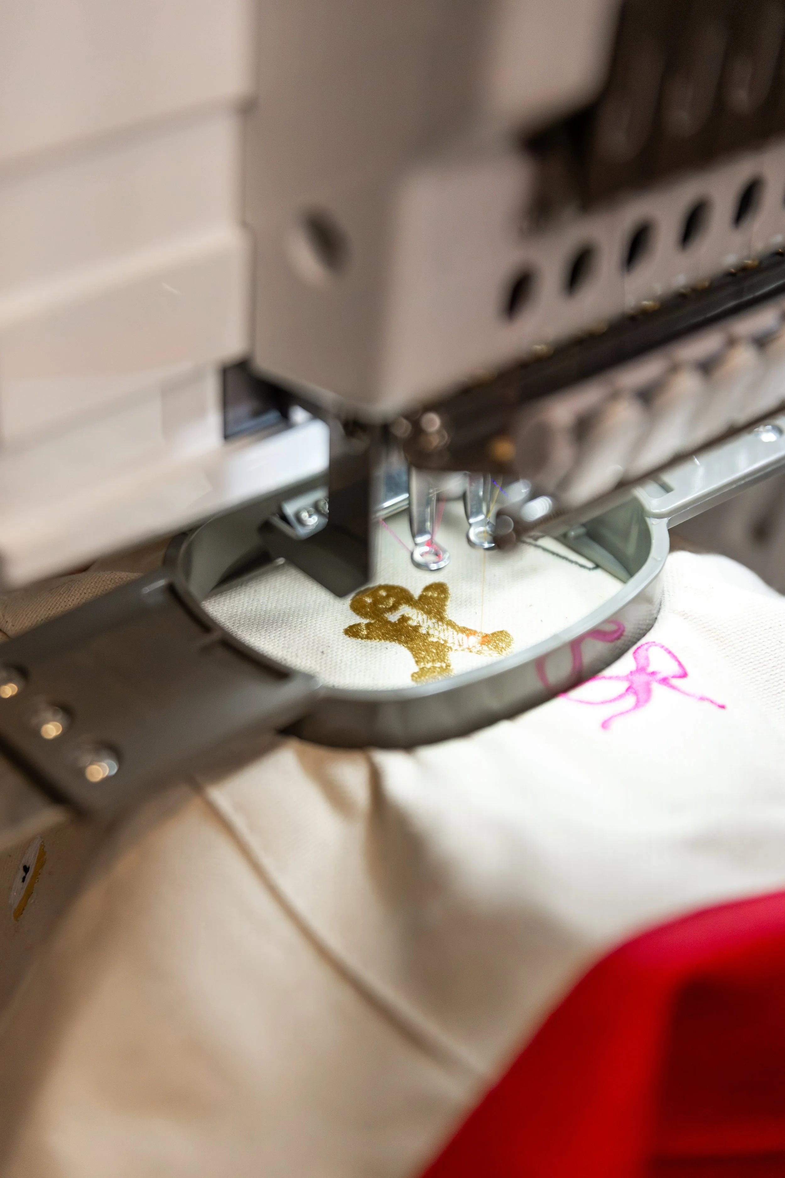 A sewing machine sewing an embroidered design of a pink fairy on fabric.