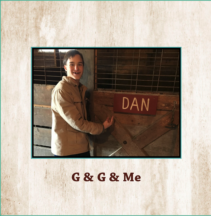 A young boy smiling and pointing at a wooden barn door with a red sign that says 'DAN'.
