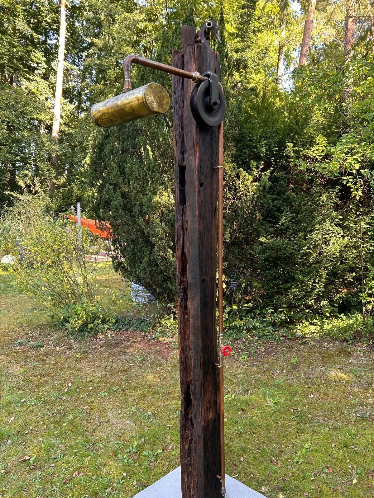 Alter Wasserpumpenknopf an einem Holzpfosten im Garten.