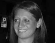 Una donna sorridente con capelli castani, in un ambiente in bianco e nero.