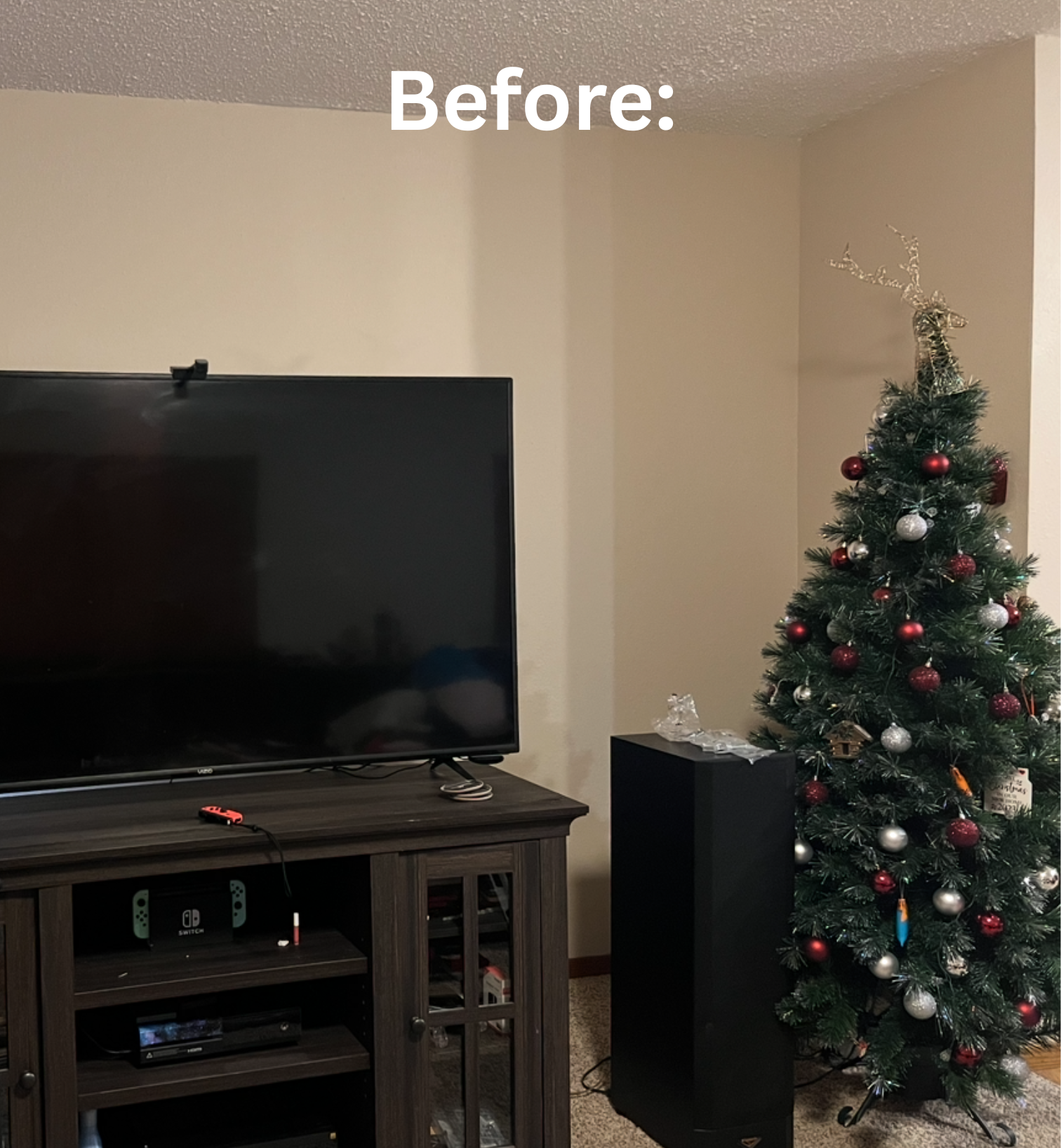 A living room corner with a flat-screen TV on a wooden stand, and a decorated Christmas tree. Showcasing the before photo of the living room accent wall.