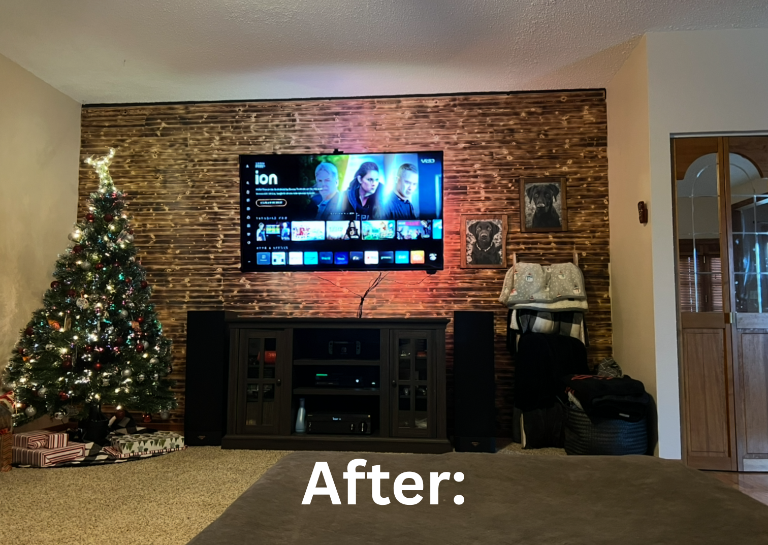 Living room with a decorated Christmas tree on the left, a wall-mounted TV in the center, with a TV stand underneath. Showcasing the after photo of the living room burned wood accent wall.