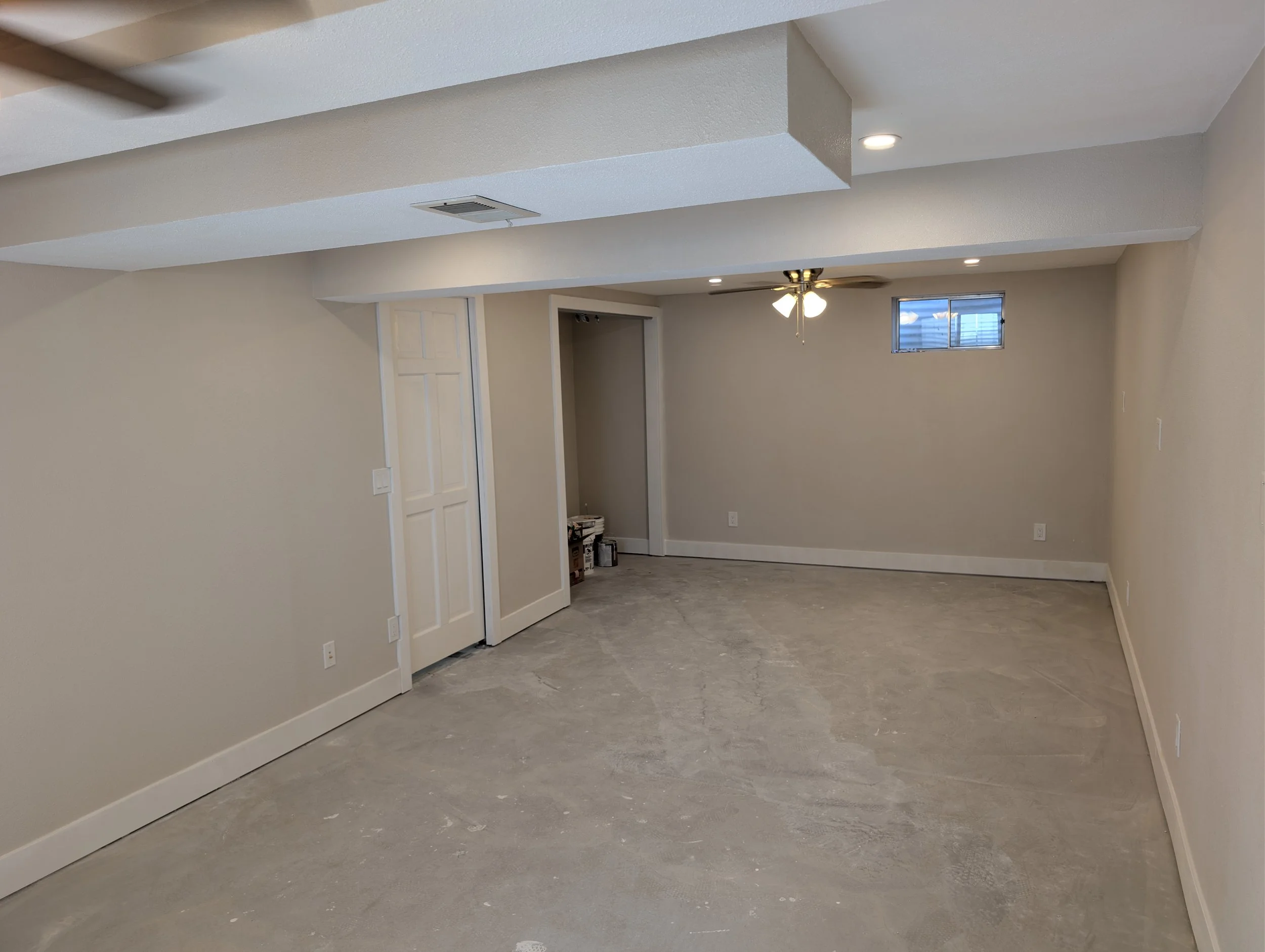 Living room with beige walls, ceiling fan, small window, and new gray stone-like flooring.