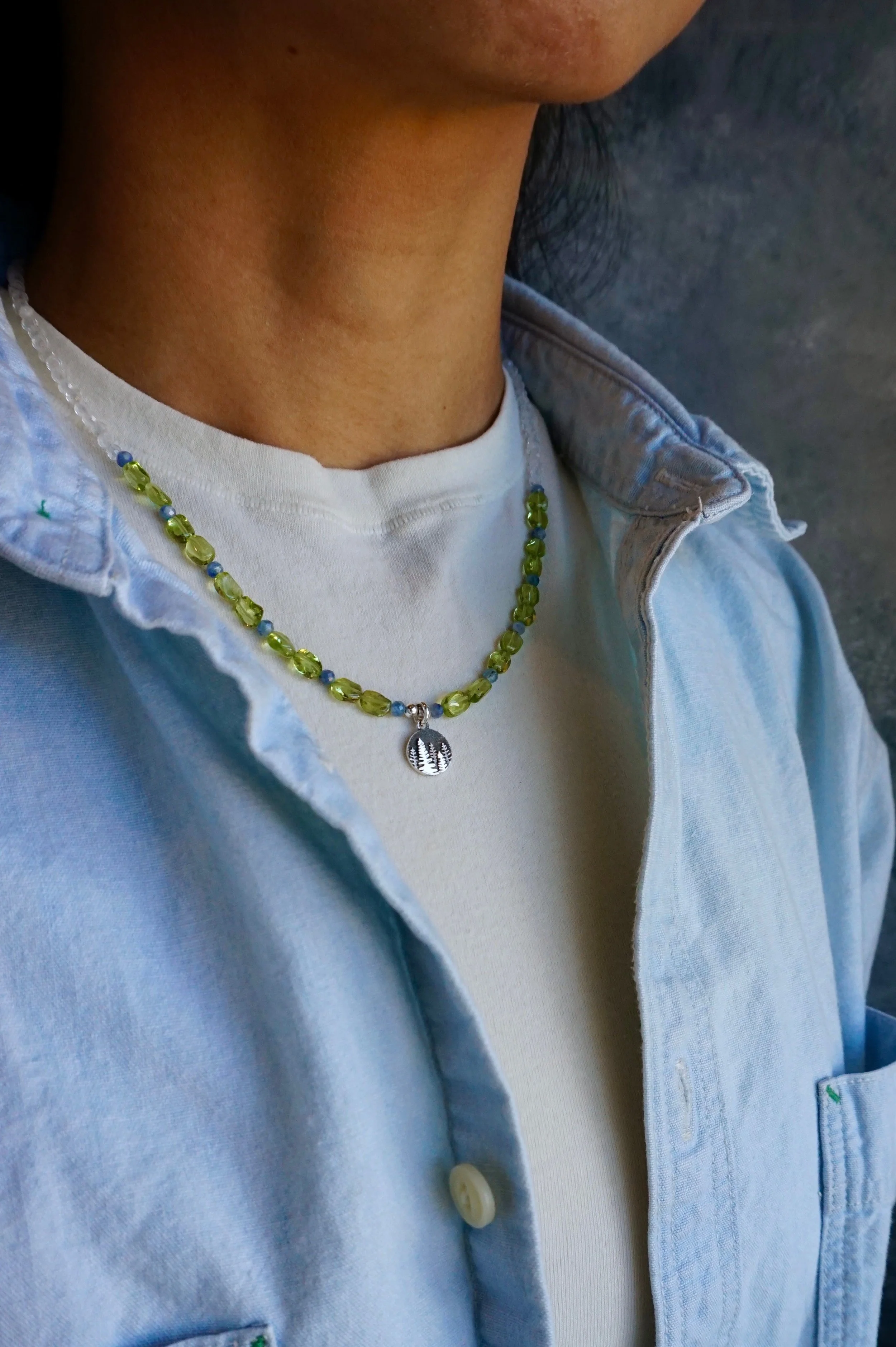 Jeweliana Studio Lake Tahoe Thailand hand-made pine tree silver pendent peridot nuggets blue kyanite beads and rock crystals paired with white t-shirt and denim jacket