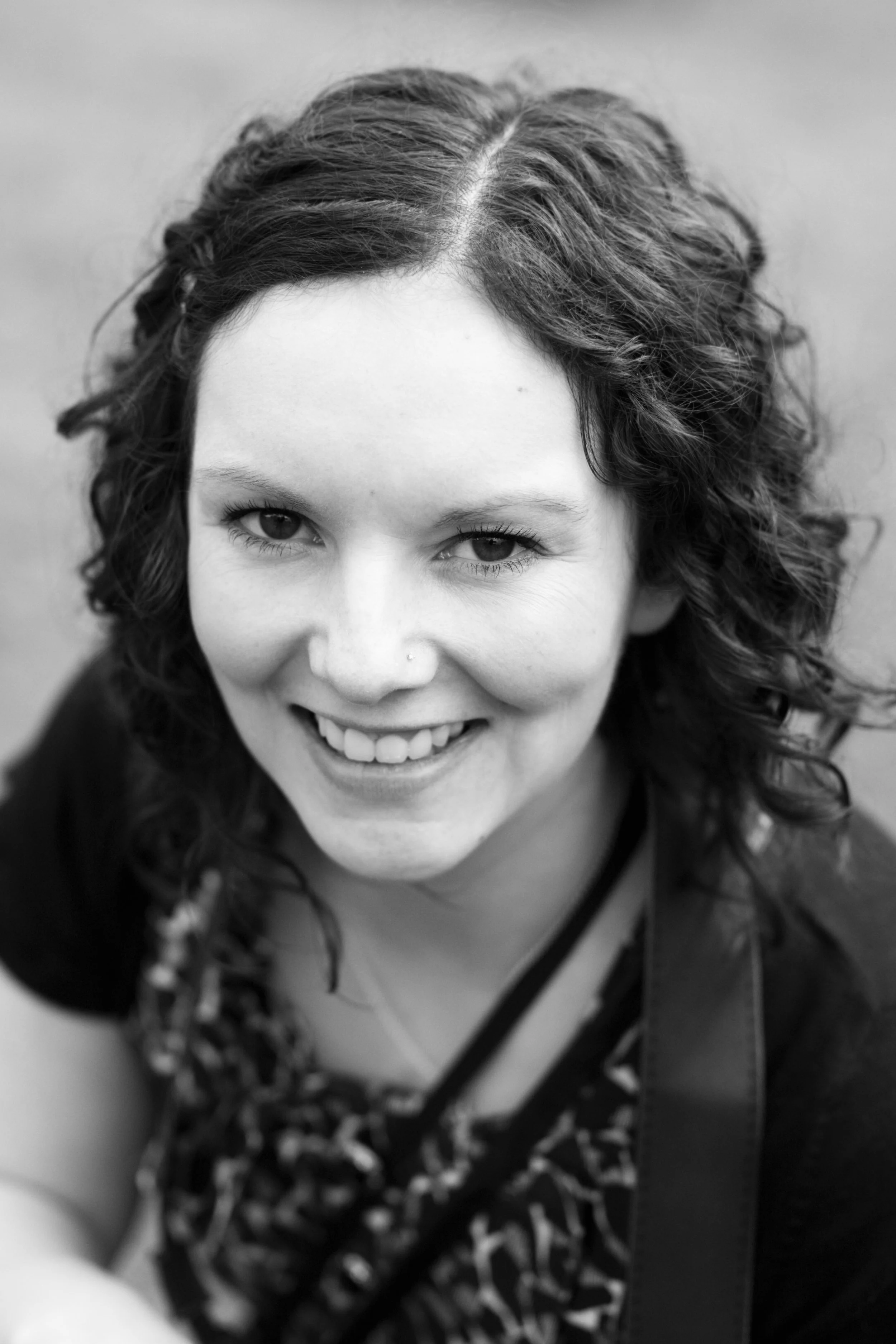 Black and white portrait of a smiling woman with curly hair.