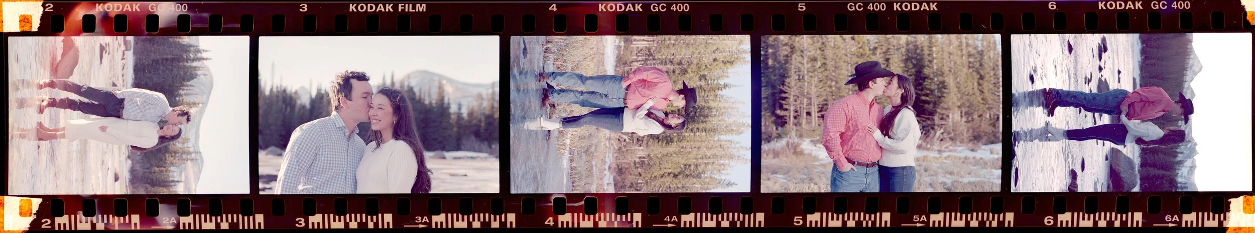 A strip of six film photos showing a couple at a snowy outdoor location with trees and mountains in the background. The couple is seen standing, kissing, and walking together in each photo.