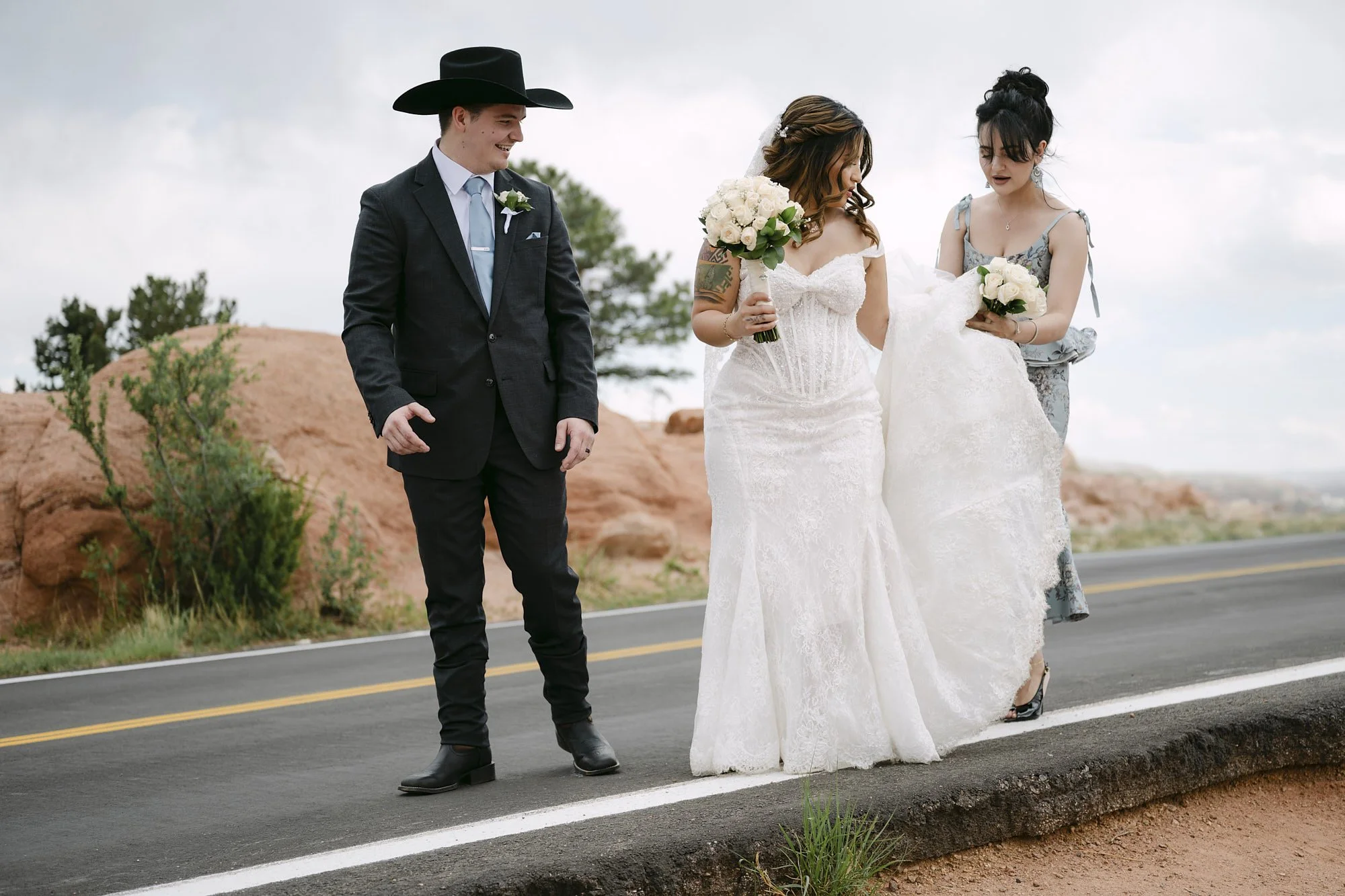 A couple is assisted by a bridesmaid while walking down the road in Garden of the Gods.