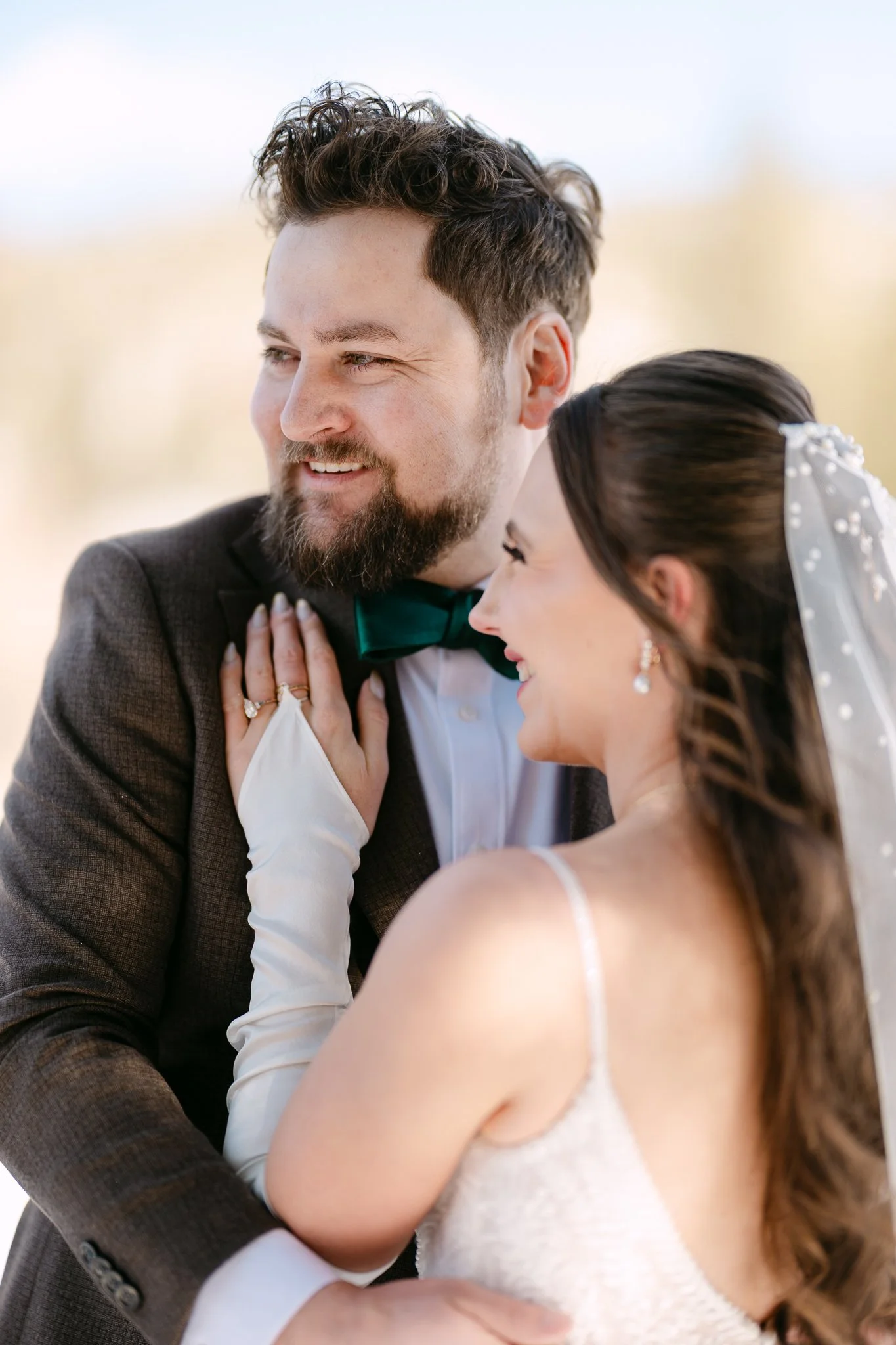 Close-up of a smiling bride and groom sharing a tender moment, outdoors during their wedding.