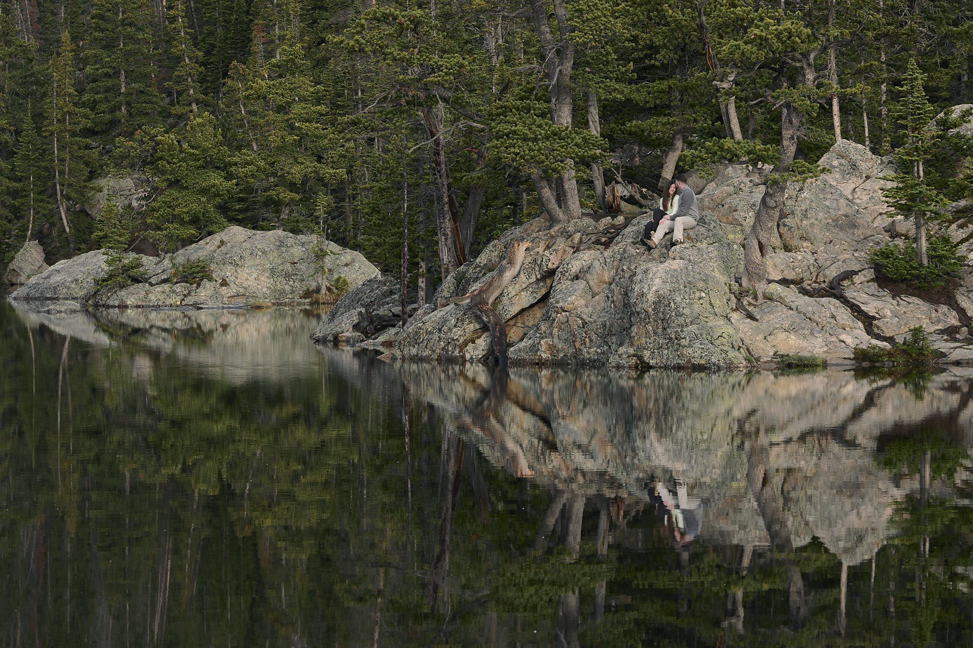 A couple sit on the shore of Dream Lake in Rocky Mountain National Park during the summertime.
