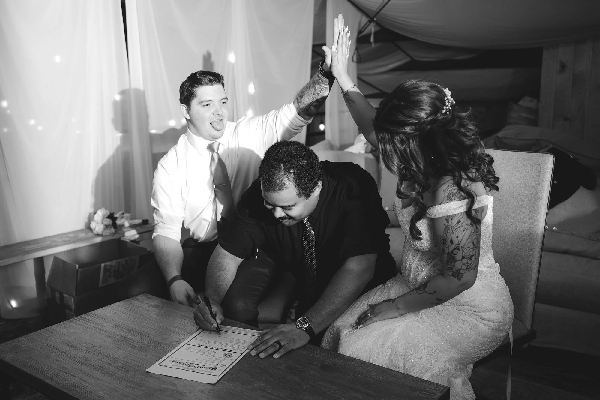 A couple high fives as their officiant signs their marriage license at Red Rocks Barn in Colorado Springs.