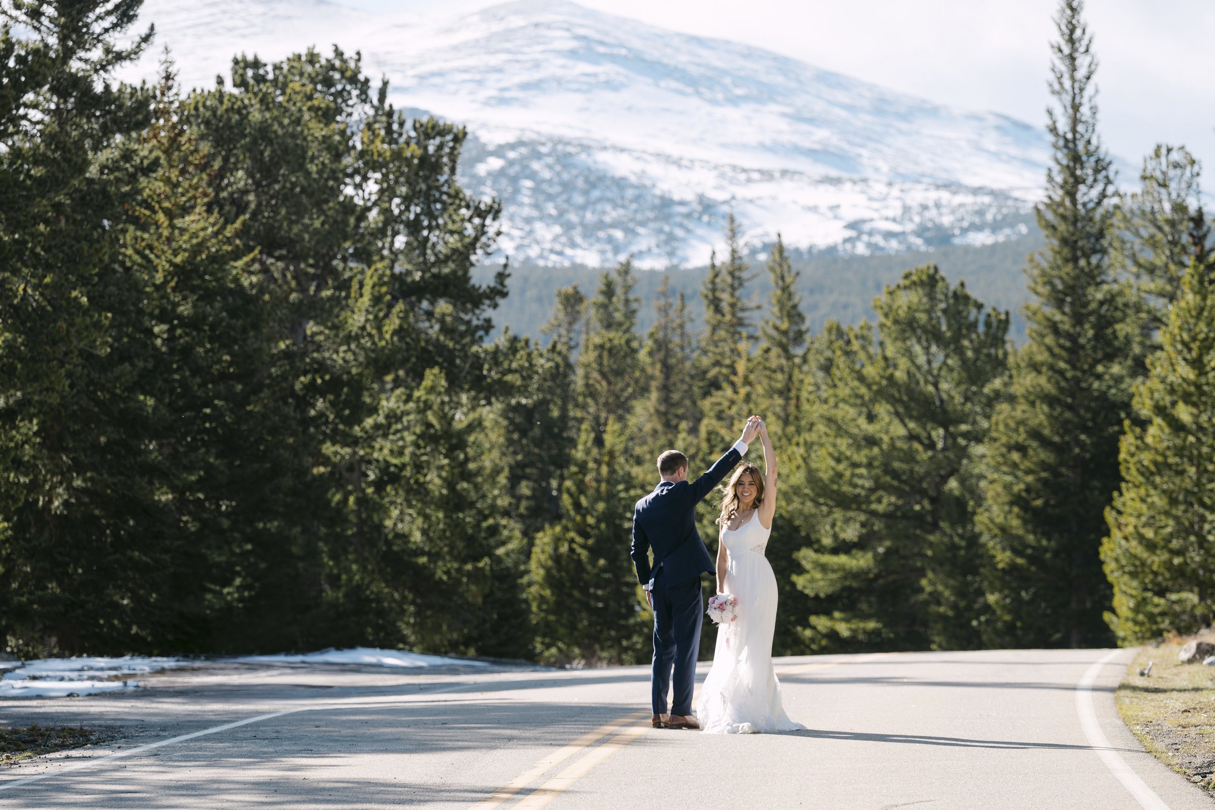 Amanda and Matt on the road to Red Rock Lake in Brainard Recreation Area, snowcapped Indian Peaks behind them in warm golden hour light