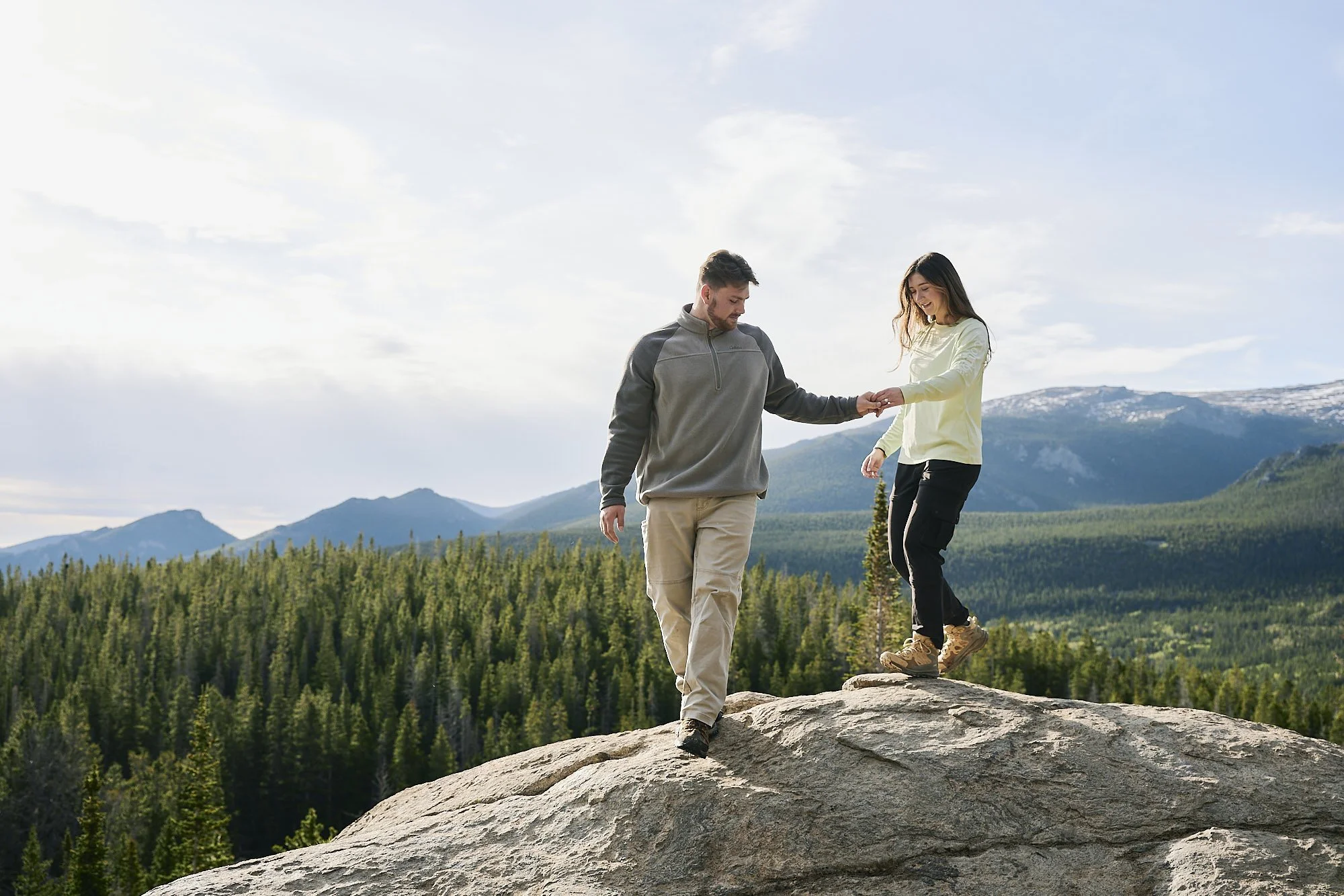 A couple holds hands as they walk down off of an overlook on the trail to Dream Lake.