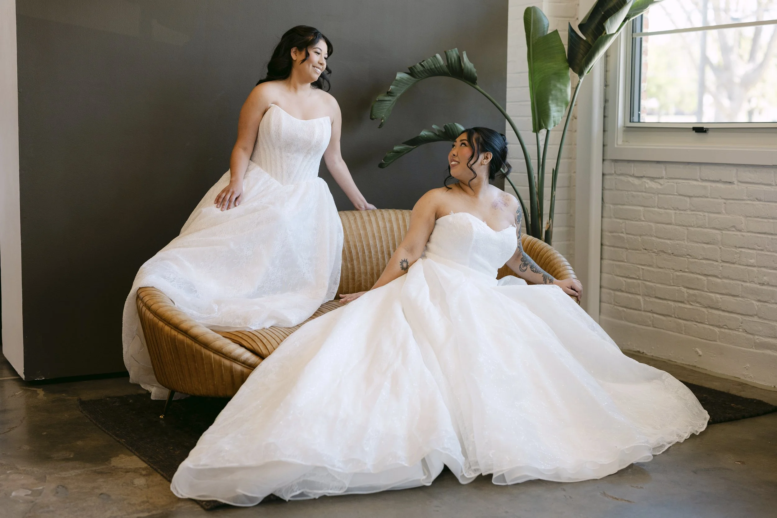 Two brides sitting together in ballgown style dresses.