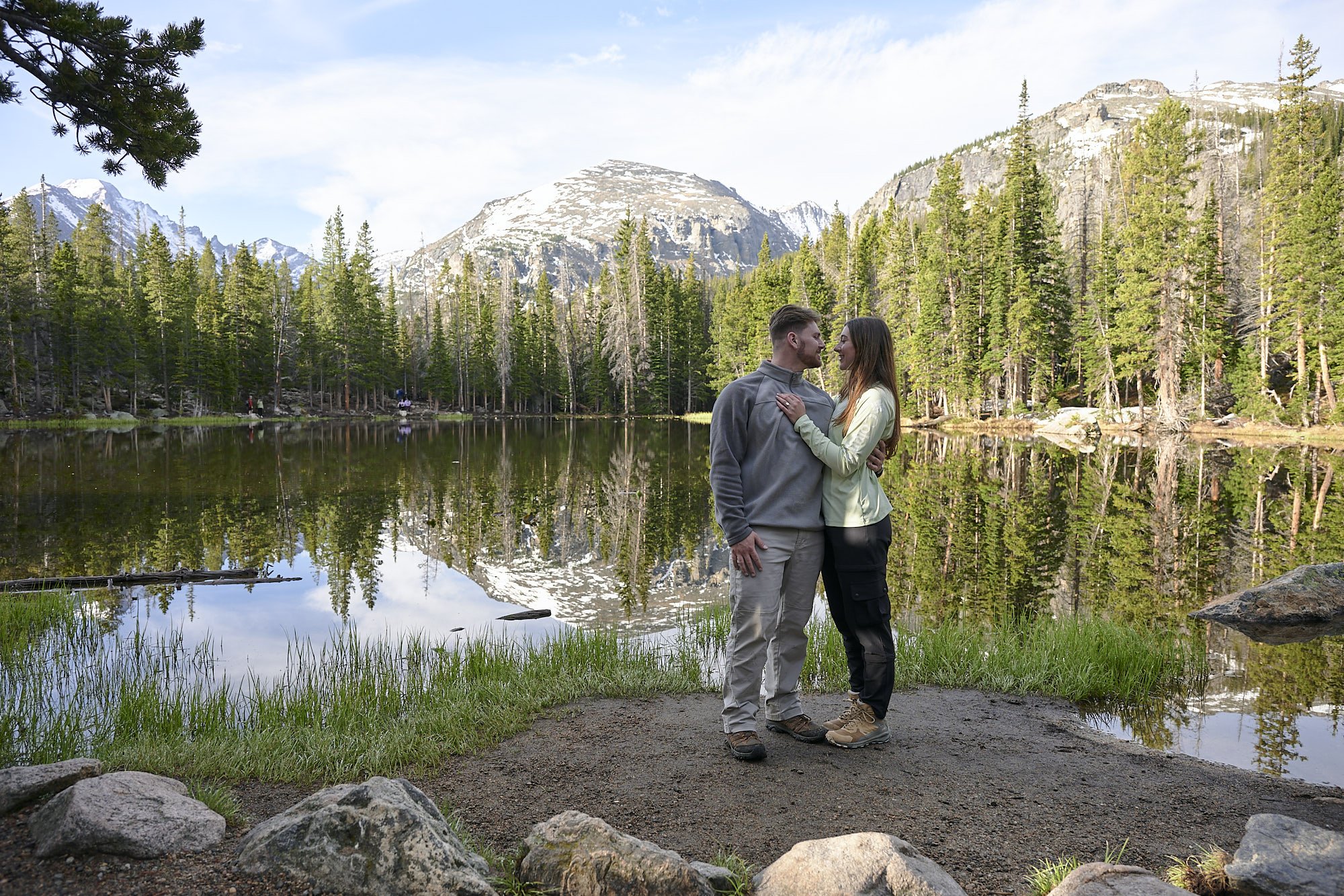 A couple embrace each other on the shore of Nymph Lake in Rocky Mountain National Park.