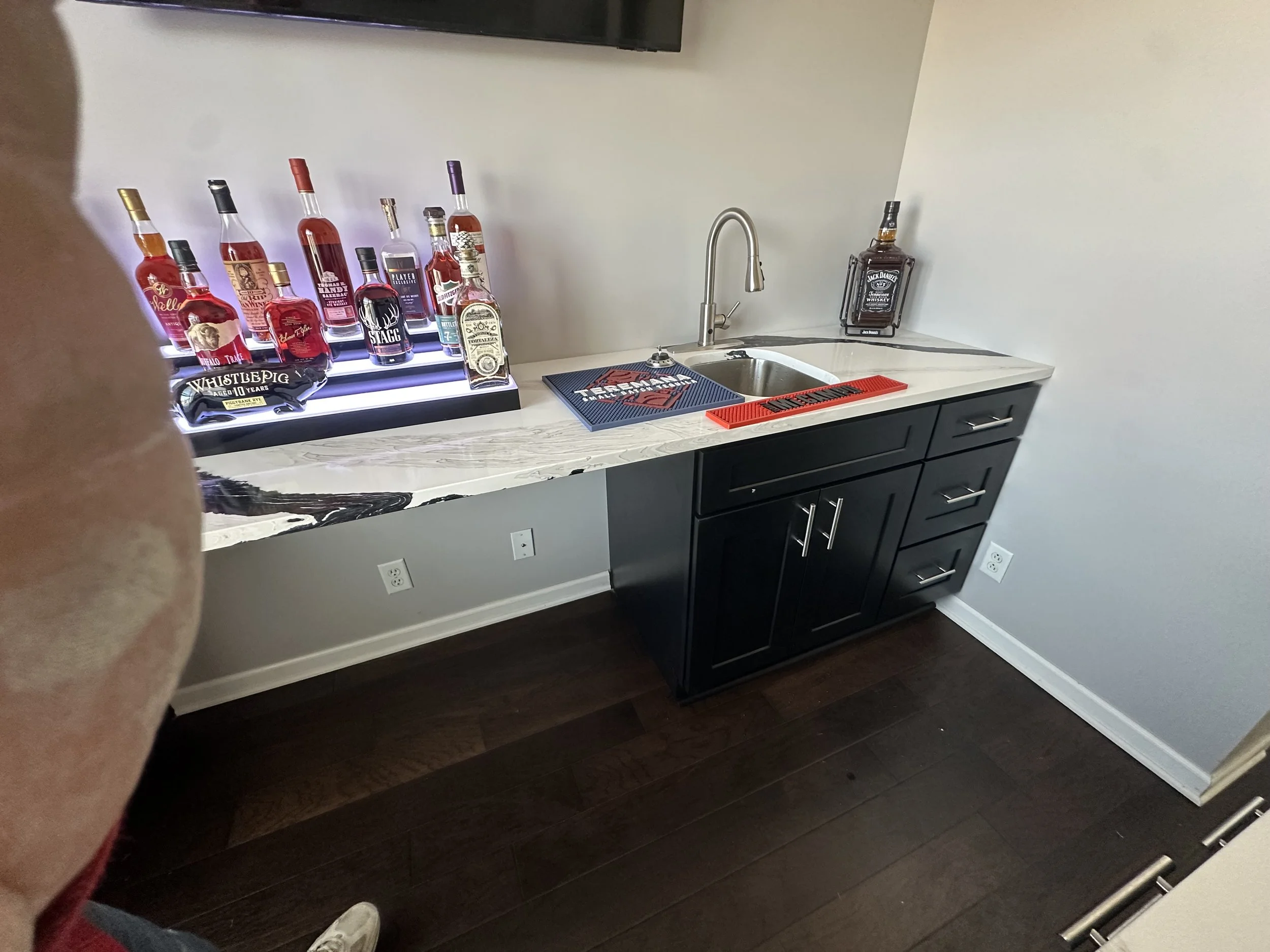 Modern home bar renovation with custom black cabinets, quartz-style countertops, integrated sink, and open shelving. Designed and installed by Dangerfield Home Improvement to elevate entertaining spaces with a clean, upscale finish.