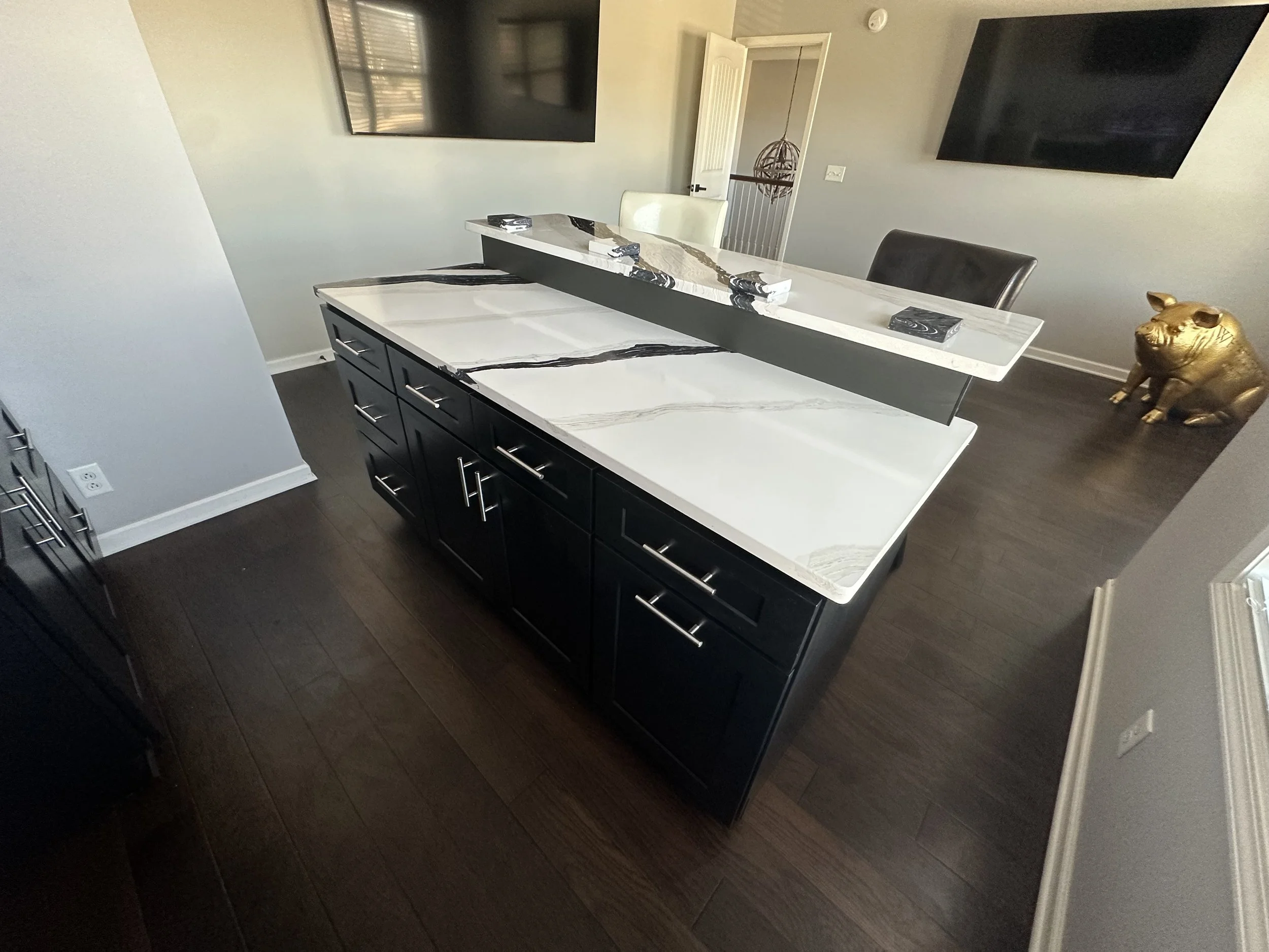 Custom kitchen island installation featuring sleek black cabinetry, modern hardware, and a luxury marble-look countertop. This custom home improvement project by Dangerfield Home Improvement adds functionality, storage, and contemporary style to the 