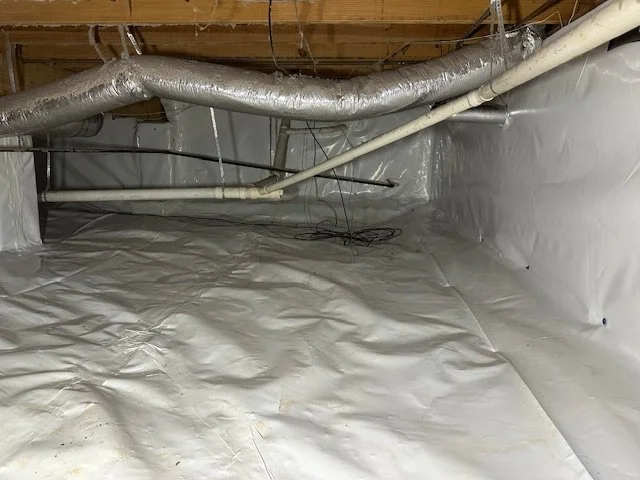 Unfinished basement or crawl space with exposed ductwork, pipes, and white vapor barrier on the floor and walls.