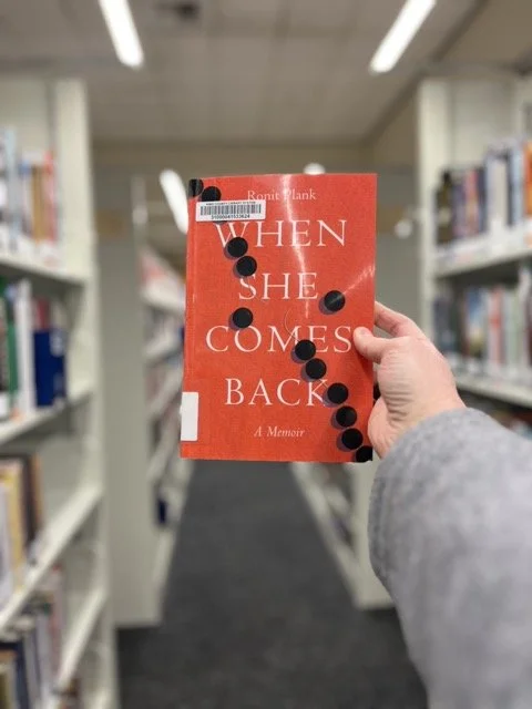 When She Comes Back by Ronit Plank, shown in the stacks at the Redmond Library