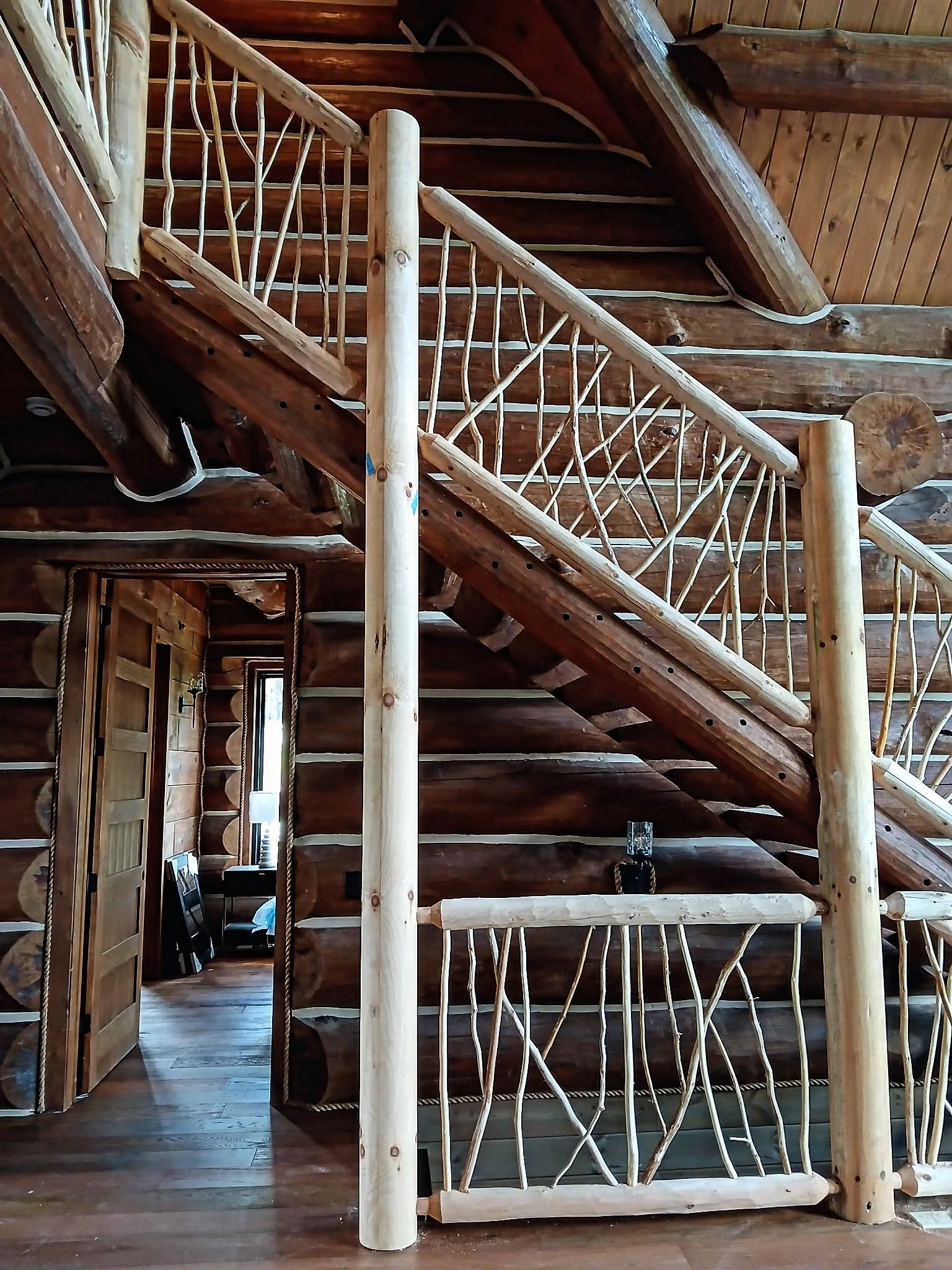 Interior staircase featuring decorative twig railing inside a traditional log cabin.