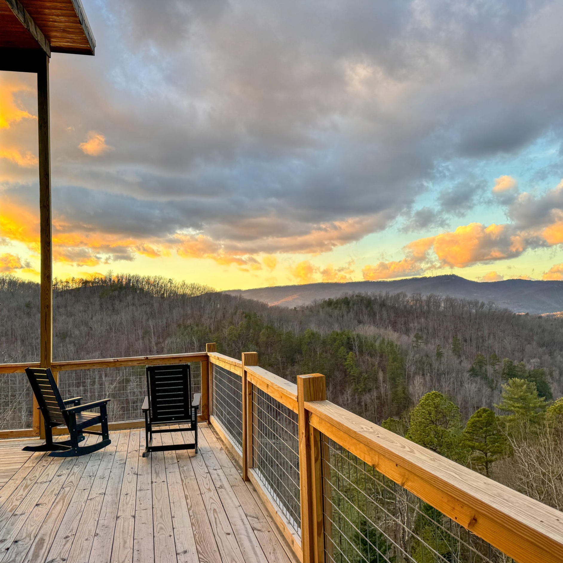 Hog wire railing on a mountain cabin deck with wide scenic Smoky Mountain sunset views.