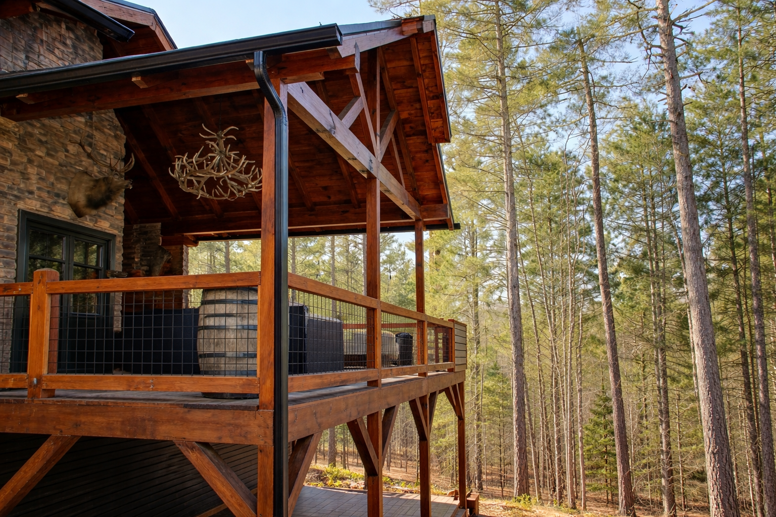 Rustic cabin porch featuring wood frame hog wire railing overlooking forested landscape.