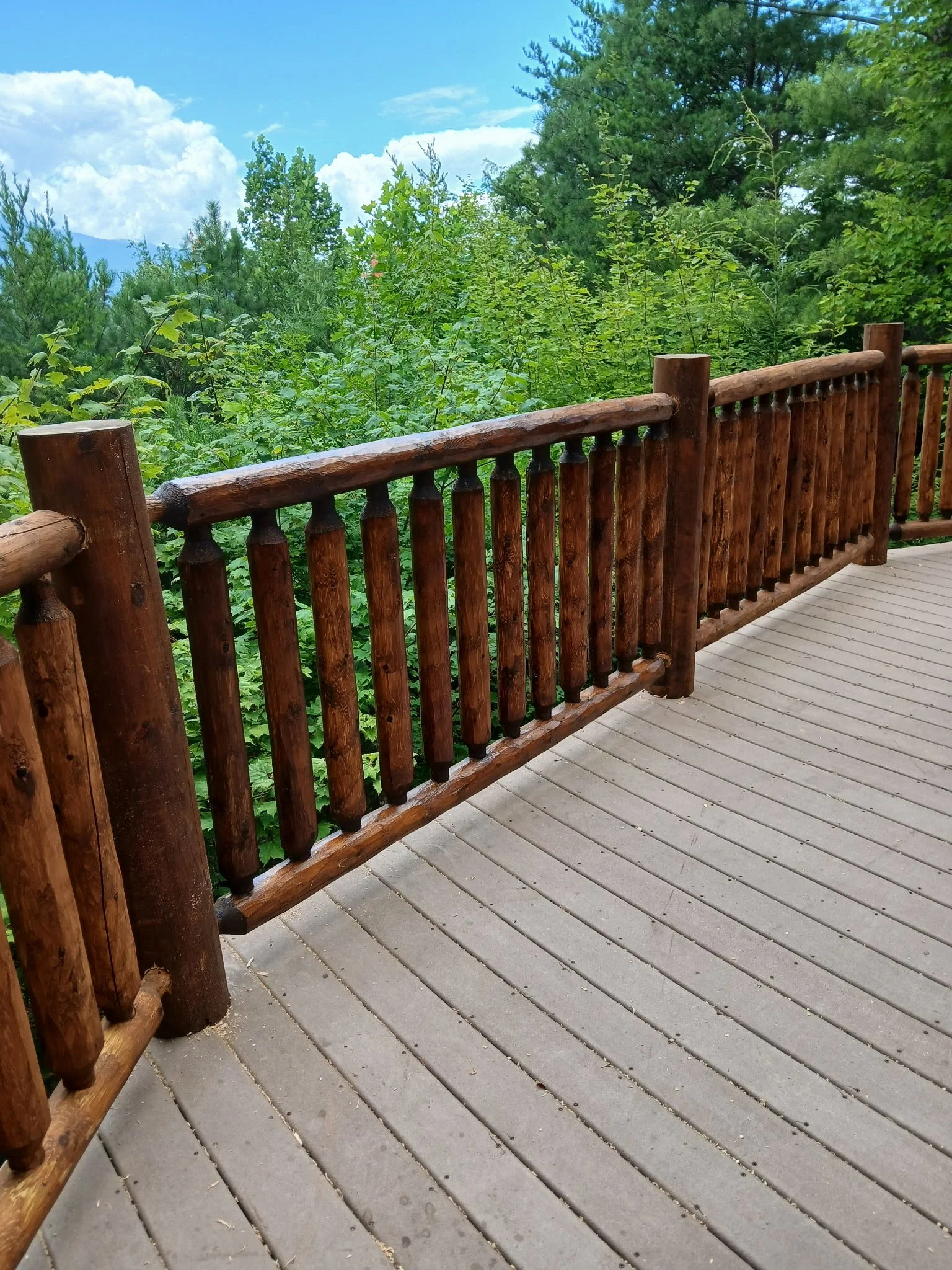 Multi-story mountain cabin exterior featuring log railings across multiple covered decks.